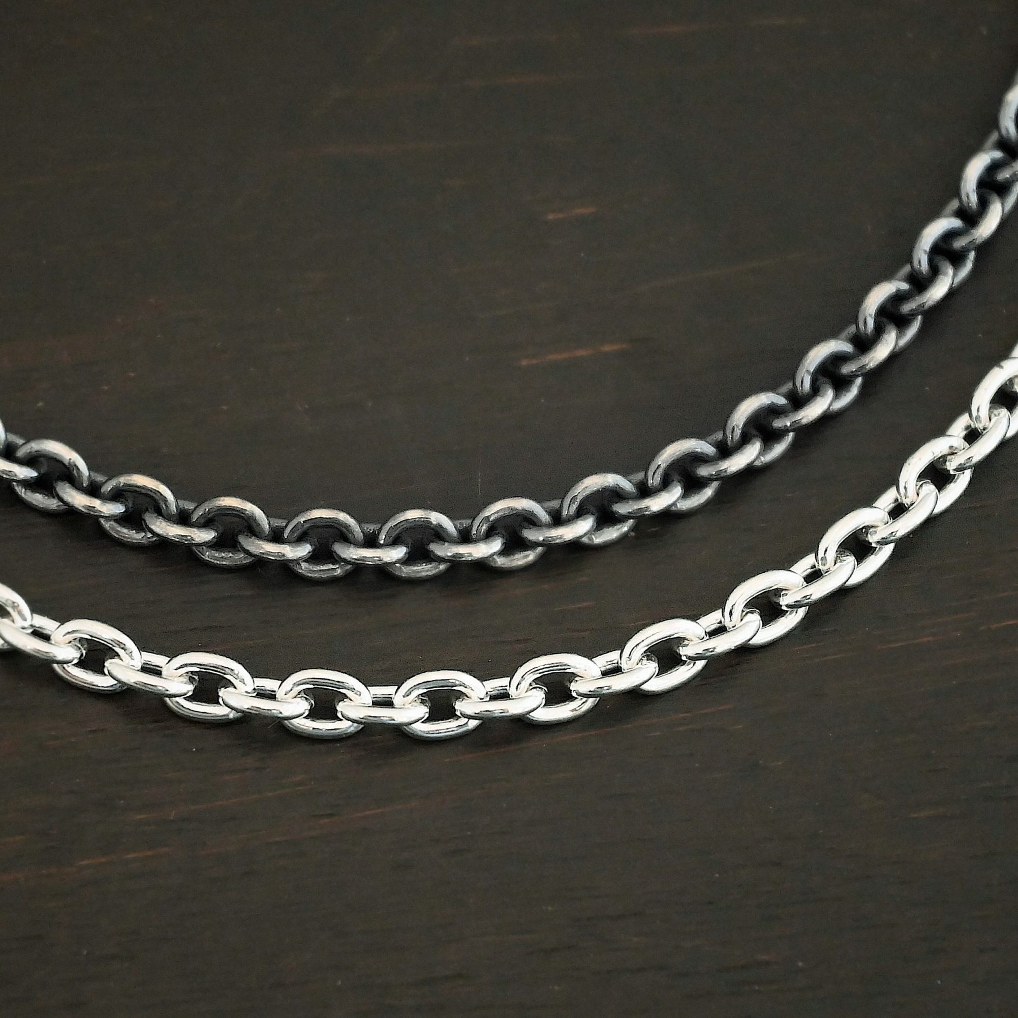 Close up of shiny and oxidized sterling silver Lauren chain with oval links laying against a dark background. Links measure 5x4mmx1mm thick.