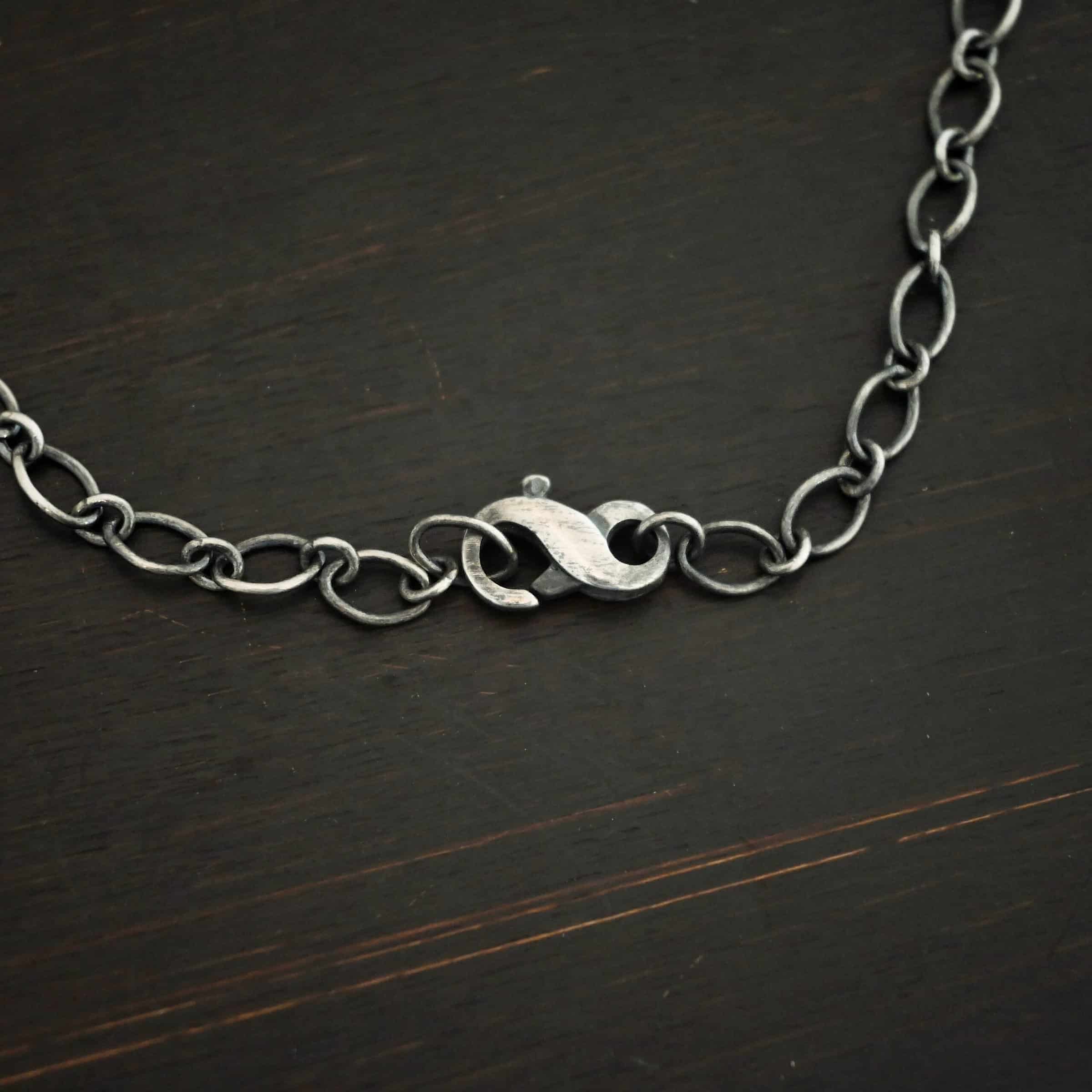 Allie Chain Oxidized sterling silver Allie chain with alternating circle and oval links laying on a dark background with the infinity clasp showing as the main focus. Oval links measure 7×4.6mm for the chain.