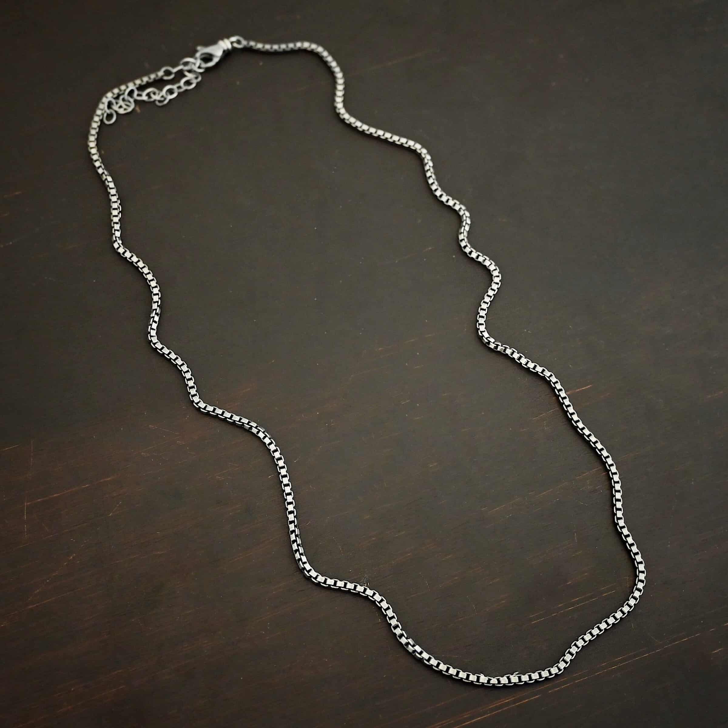 "Briggs Box" Chain as oxidized. Chain is made out of sterling silver and has box links that make up the chain. Chain is lying against the dark background. Heavy Box Chain 2.5mmx1.4mm.