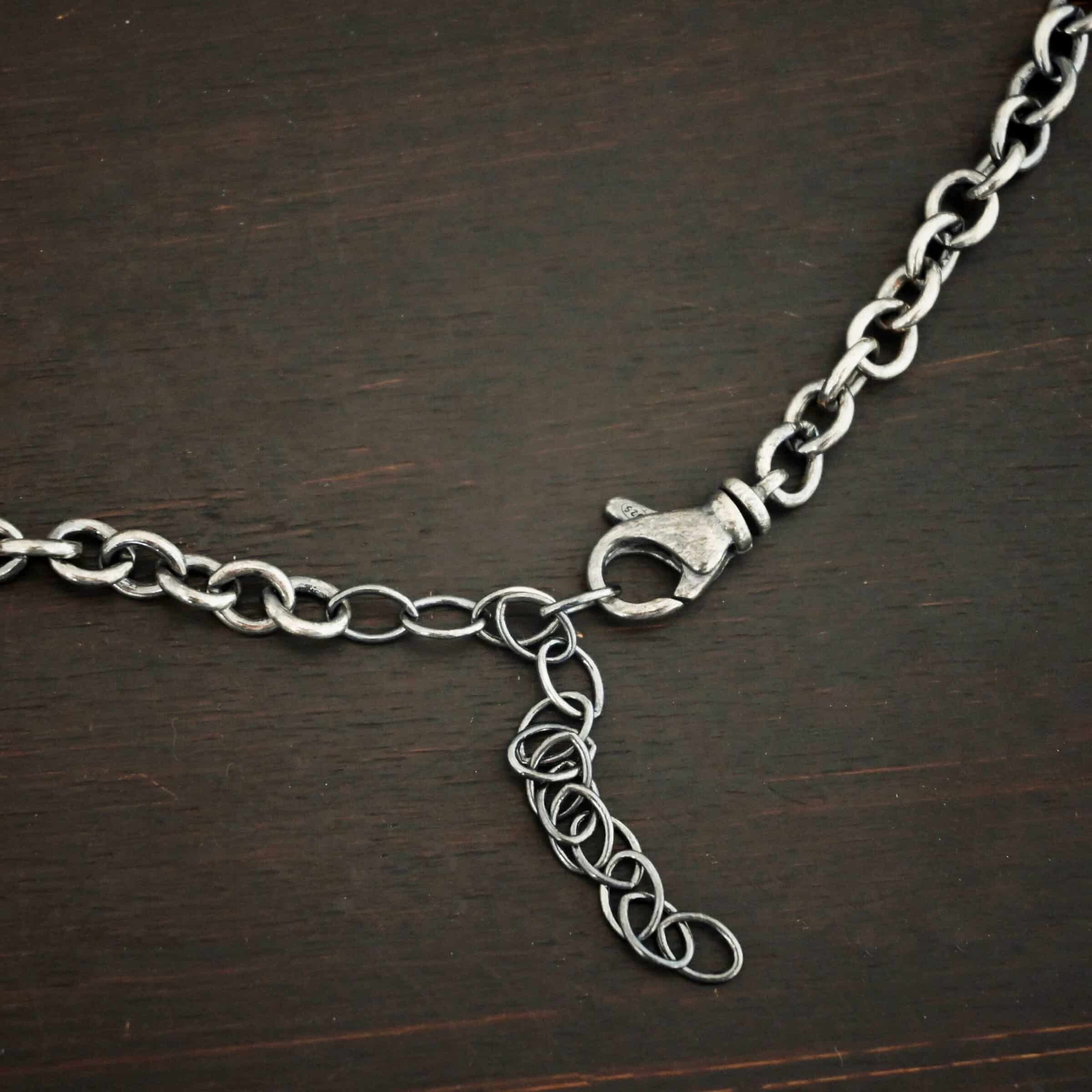 Oxidized sterling silver Joy chain with circular links laying on a dark background with the lobster claw clasp showing as the main focus. Links measure 6.5×5.4mm.