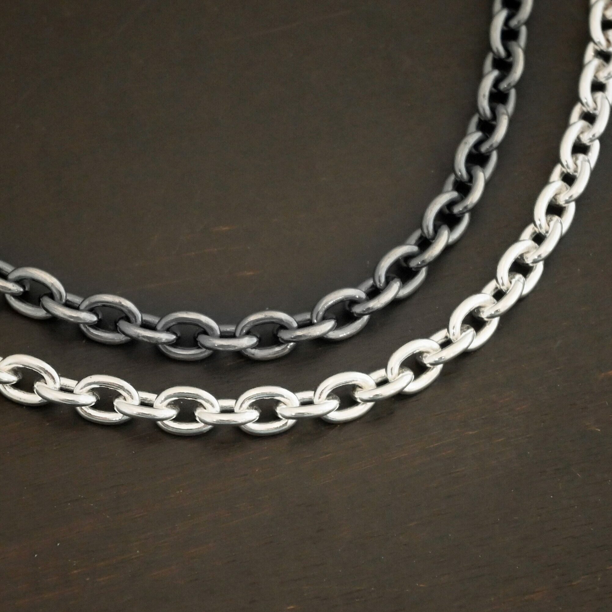 "Georgia" Chain as shown up close with both shiny and oxidized. Oxidized chain is on top and shiny is on the bottom. Heavy links measure 8x6mmx1.7mm thick. Chains are shown against a dark background.