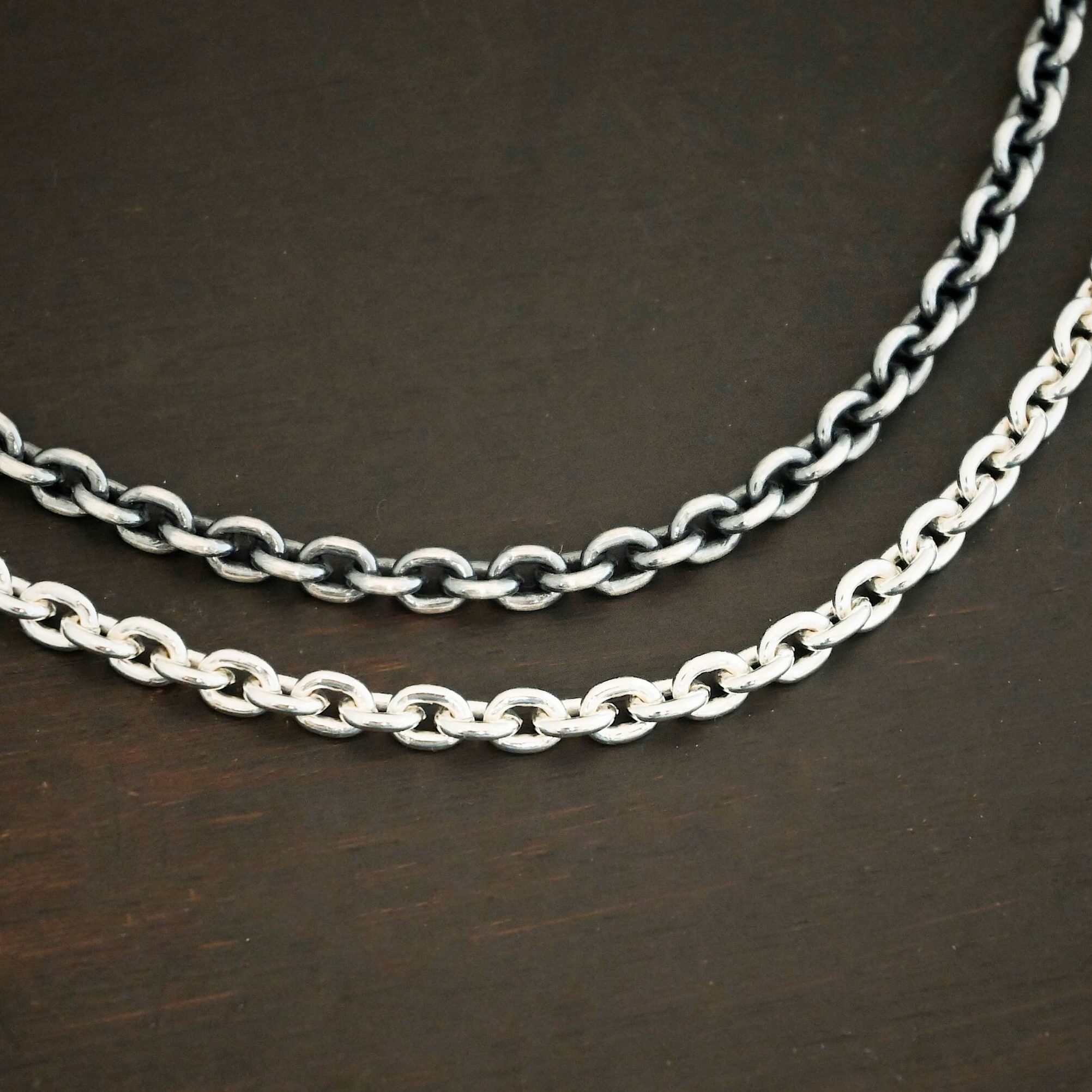 Joan Chain Close up of the "Joan" Chain as shiny and oxidized. Chain is handmade out of sterling silver and has links that are 6x5mmx1.2mm thick that make up the chain. Chain is laying against a dark background.