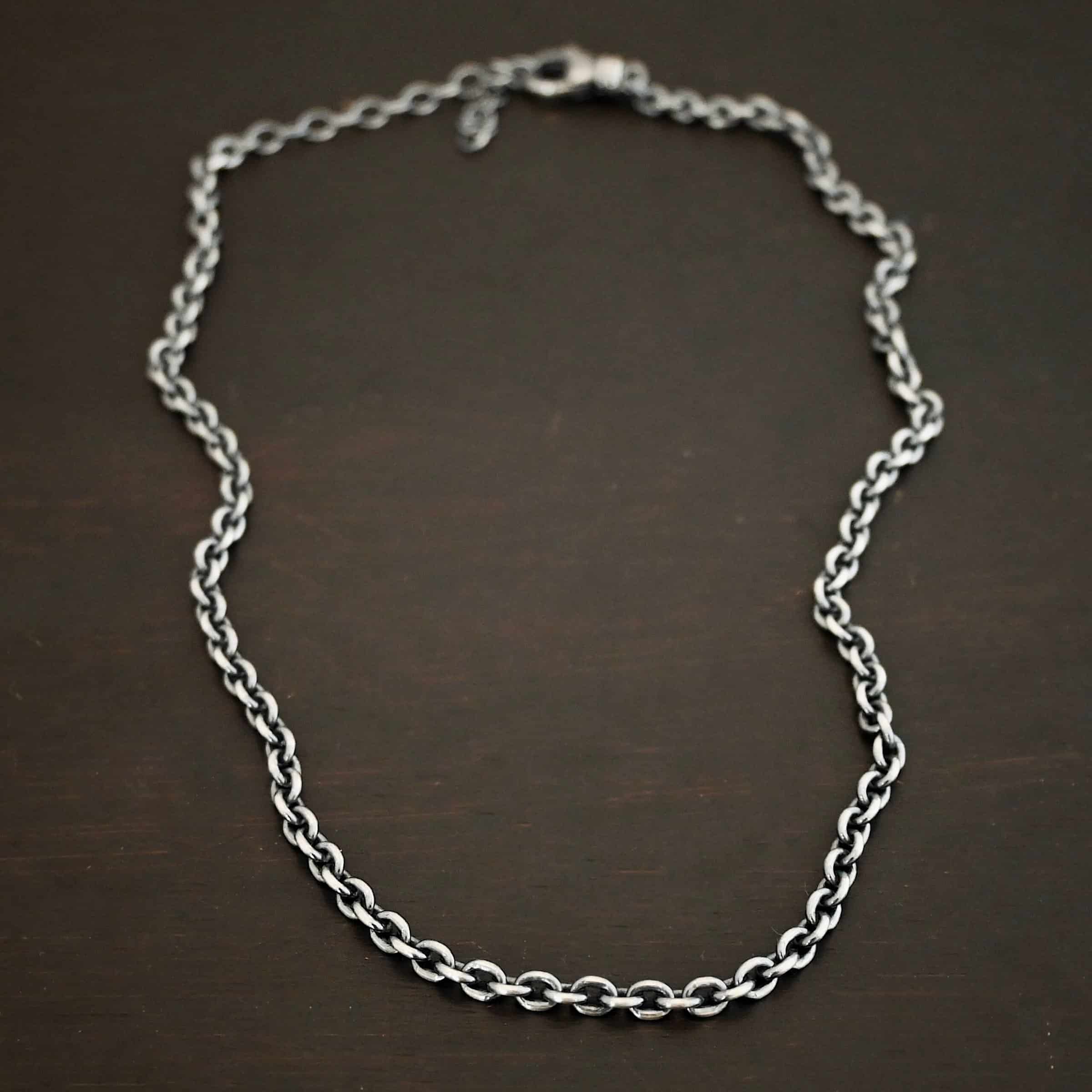 Joan Chain Oxidized sterling silver Joan Chain with oval links that are 6x5mmx1.2mm thick. Chain is lying on a dark background.