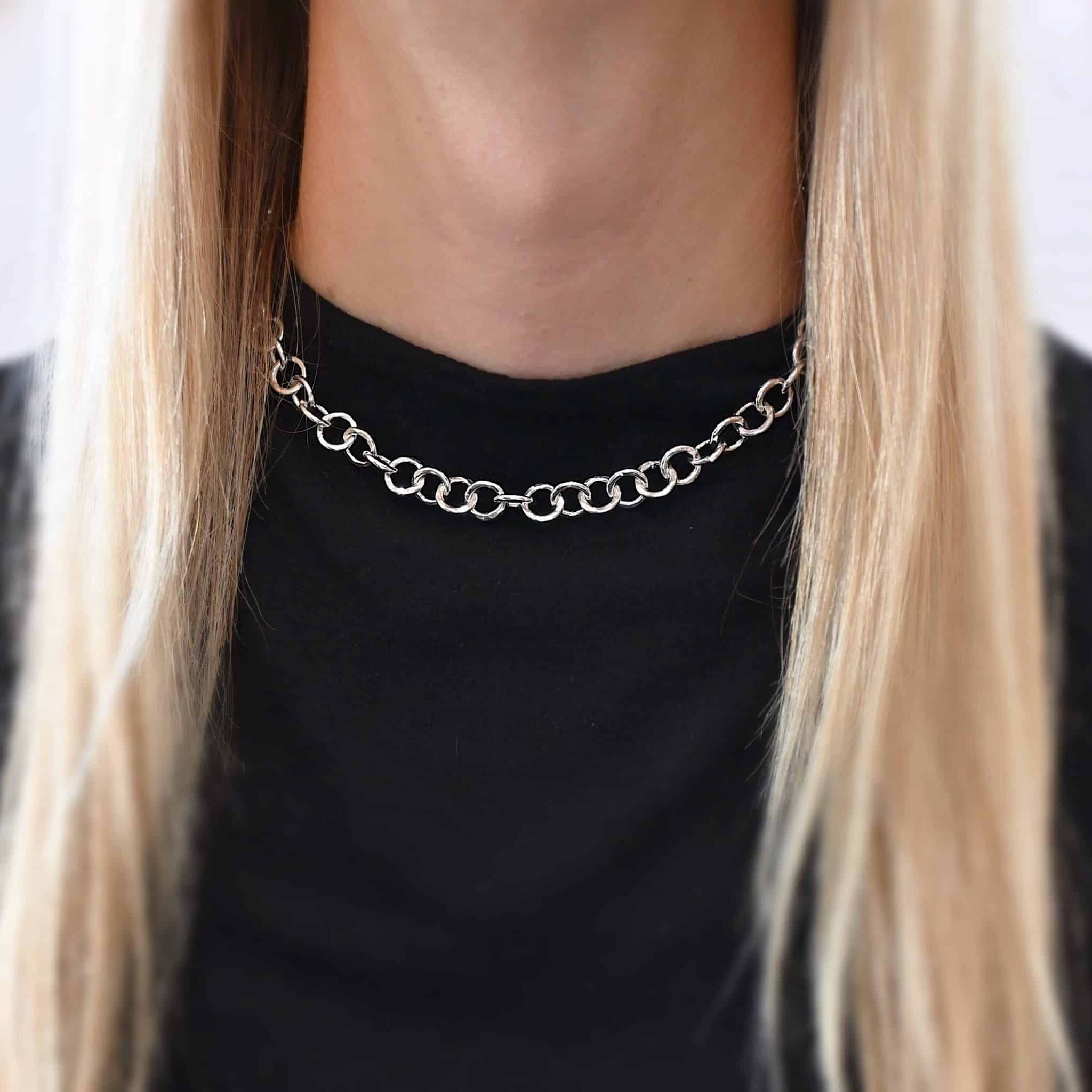 The "Wyatt" Chain as shown on a model. Chain is shown at 16 inches long and shiny. Chain has thick hammered sterling silver circle links. Model is wearing a black t-shirt.