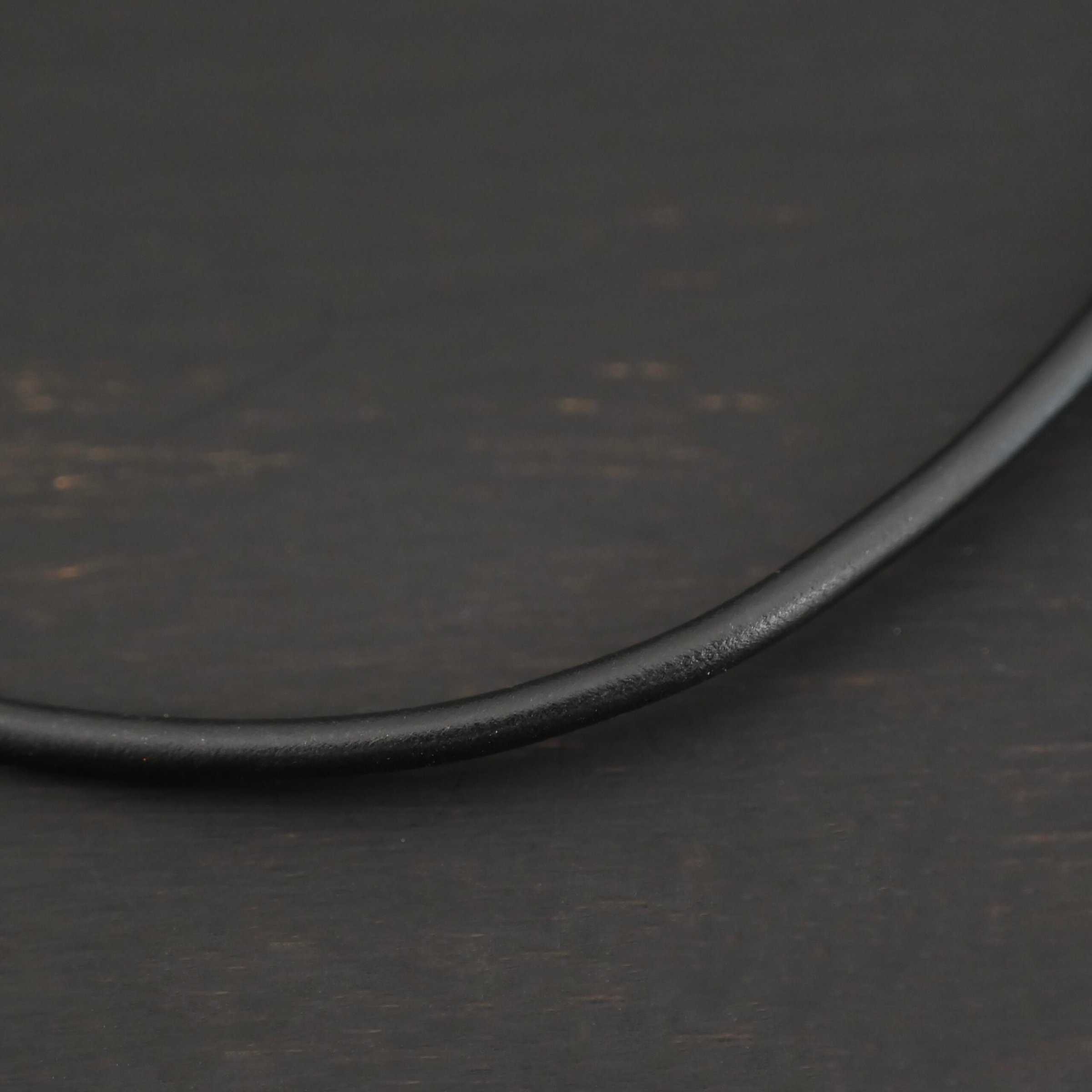 Close up of the "Wren Wire" Chain. Made out of black leather. Chain is shown against a dark background.