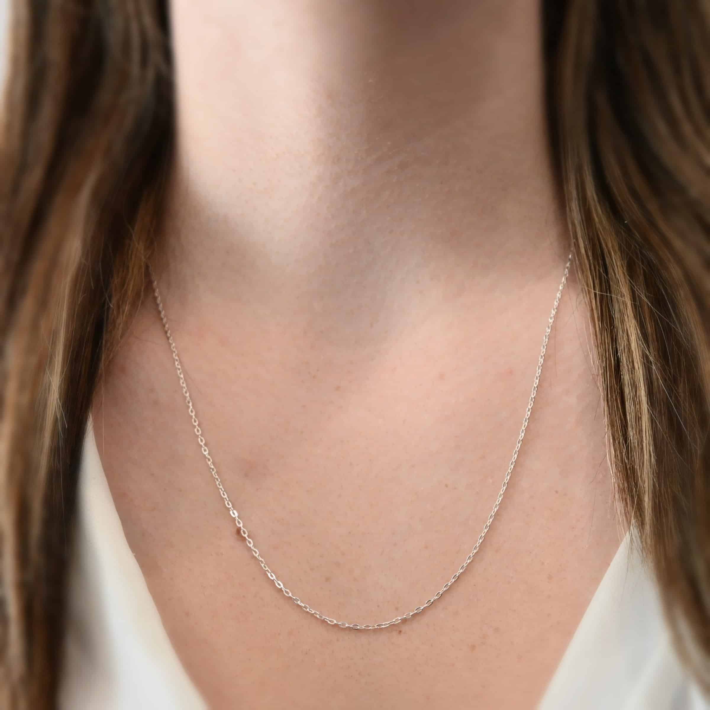 Cassandra Chain 22-25" Shiny "Cassandra" Chain as shown on a model. Chain is shown at 22" long and shiny. Chain has 2x2mm links. Model is wearing a white v-neck shirt.