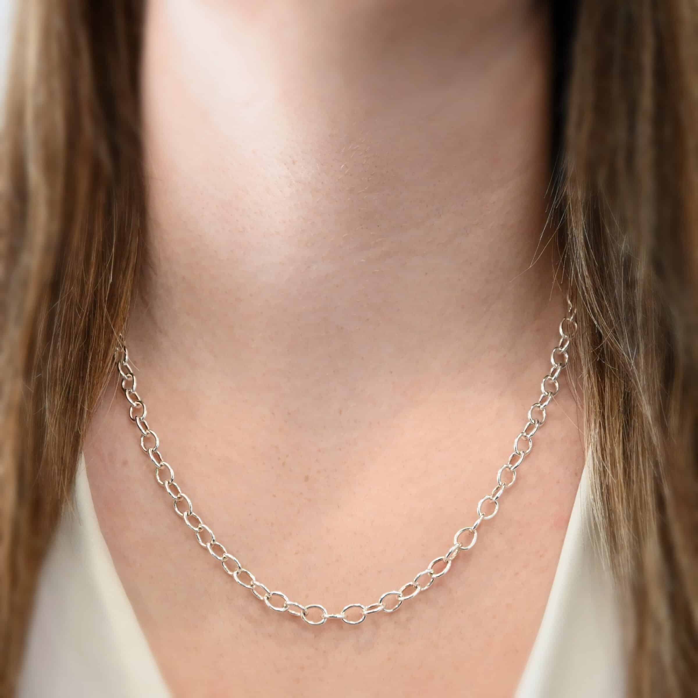 Jay Chain 20" Shiny Close up of the "Jay" Chain as shown on a model. Chain is shown at 20" long and shiny. Chain is handmade out of sterling silver. Links measure 7.2×5.7mm. Model is wearing a white v-neck shirt.