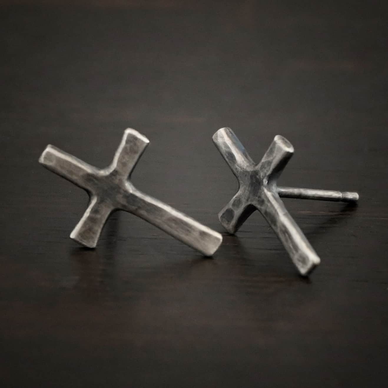 Healer Earrings Photo of the "Healer" earrings. The small crosses are hammered and oxidized, with posts on the back of them. Earrings are lying against a dark background.