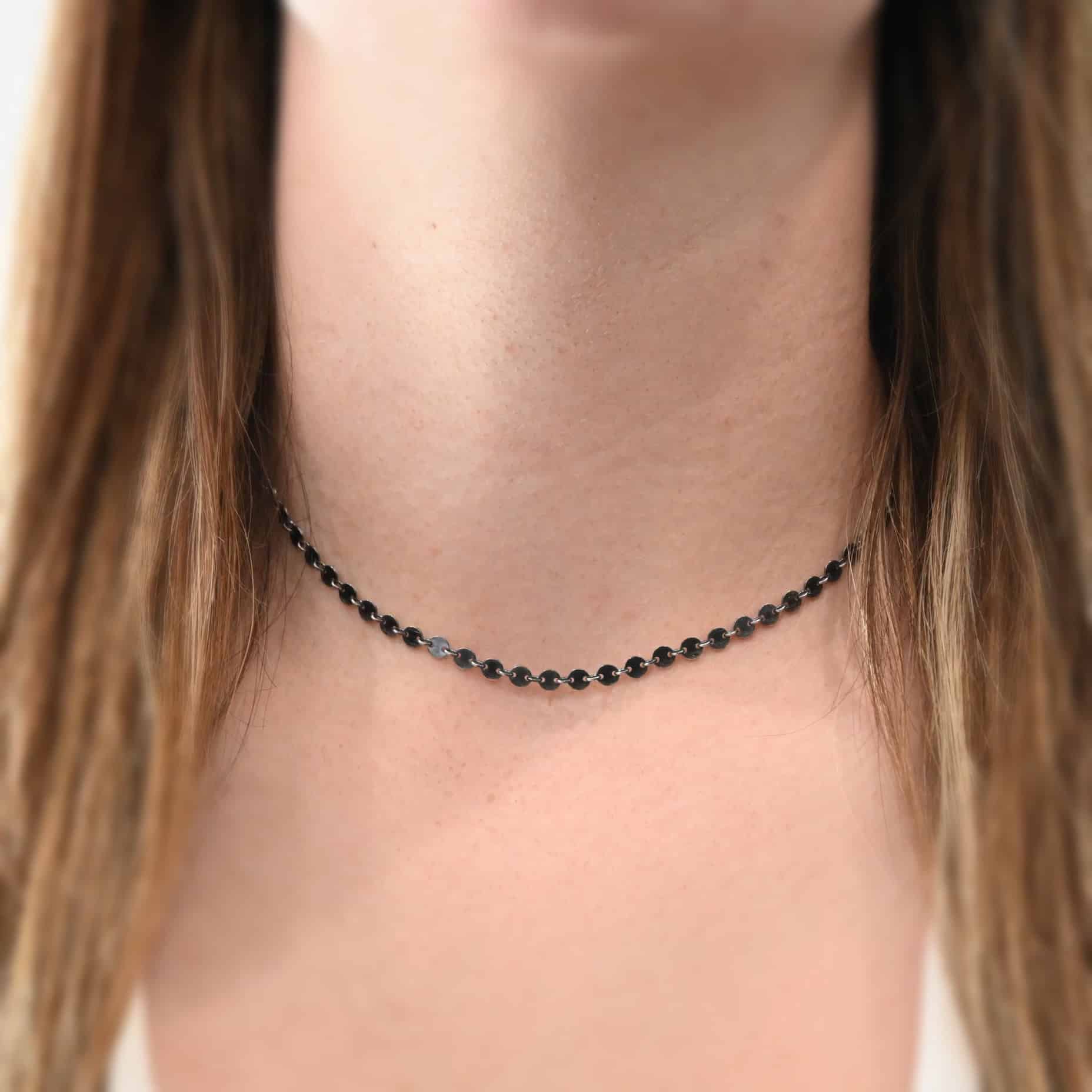 "Gypsy Coin" Chain as shown on a model. Chain is shown at 15" long and as oxidized sterling silver. 4mm disks connected with jump rings. Model is wearing a white v-neck shirt.