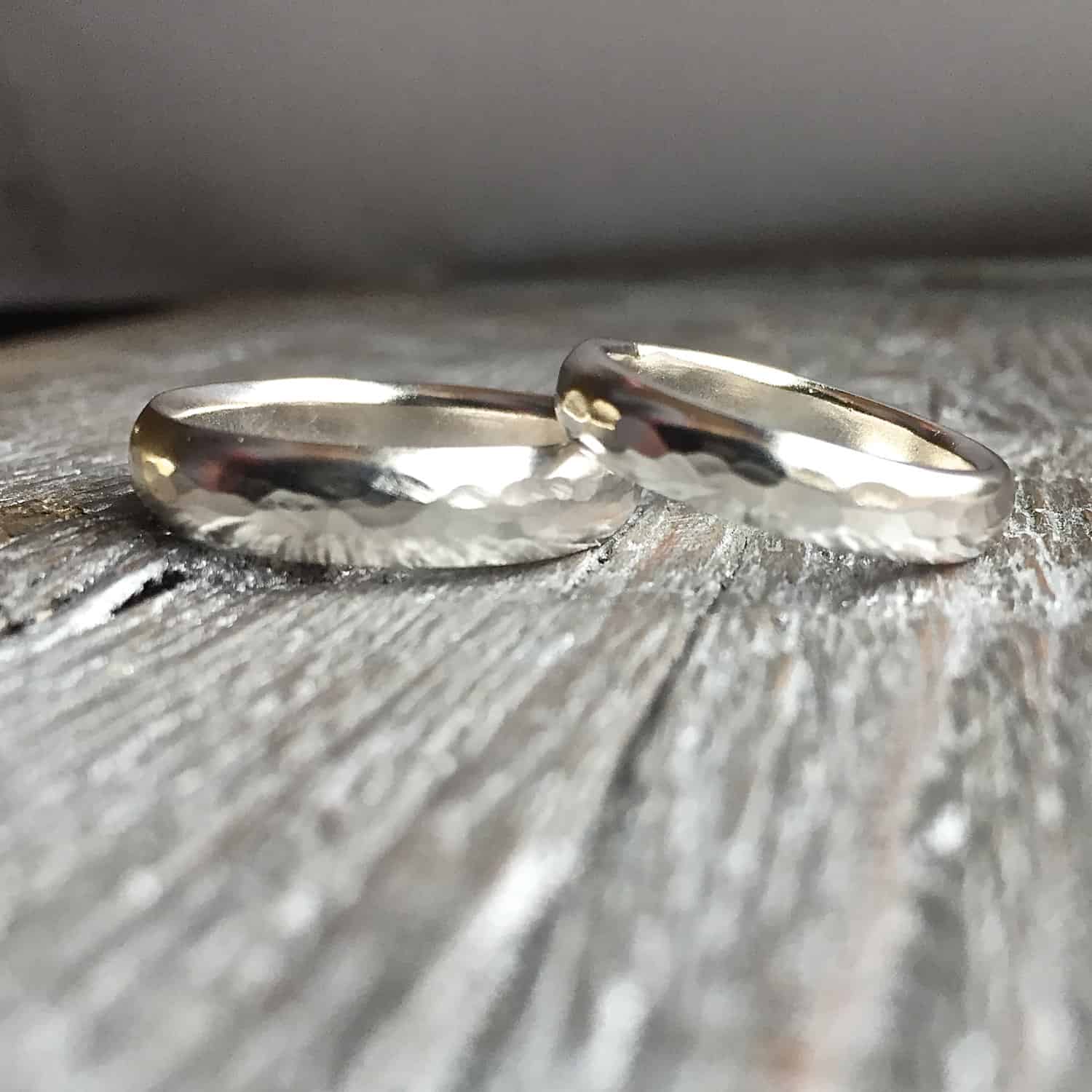 My Best Friend Wedding Band Photo of the "My Best Friend" Wedding Bands. They are both made out of shiny sterling silver and hammered. They are thicker bands of silver. One rests on top of the other. Both are against a wooden background.