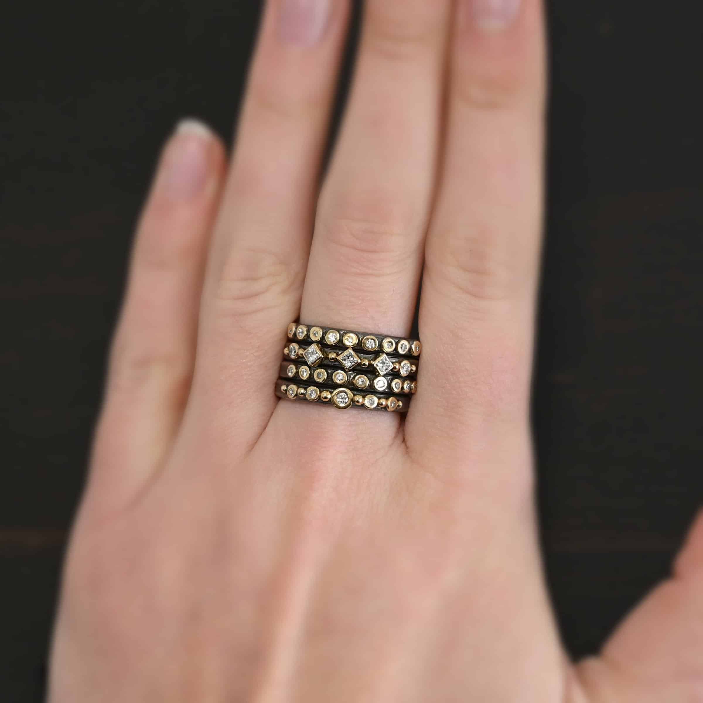 Juliet Ring Photo of the "Juliet" Stacker rings. Made out of sterling silver, gold, and genuine diamonds. The top ring has nine diamonds, all set in gold and right next to each other, going across the band of the ring. The second stacker ring has five diamonds set in gold, and six gold balls, each separating the diamonds with one before the first diamond and a gold ball after the final diamond. The third ring has five diamonds and again, six gold balls, the same as the first stacker, but the diamonds are different shapes. The final stacker is the same as the first, with nine diamonds set in gold. Each ring is worn on the same finger by a model.