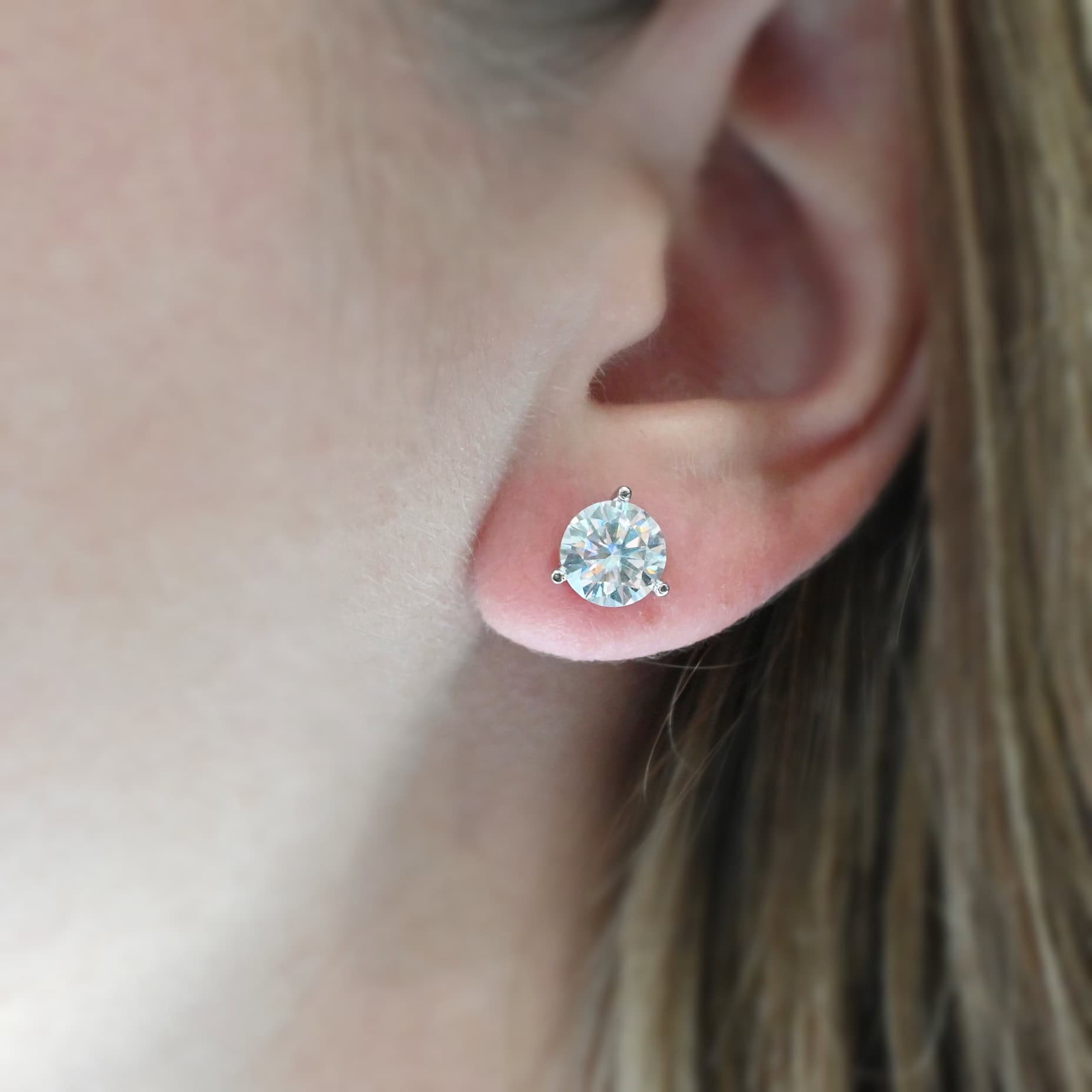 Jacquline Kennedy Earrings Close up of the "Jacqueline Kennedy" Earring. Made out of sterling silver & moissanite. There are two moissanite stones, one for each earring. Each moissanite is 1.5 carats for a total of three carats for the earrings. Come with backs that thread on the earrings to keep them from falling off. Earring is worn by a model to demonstrate size.