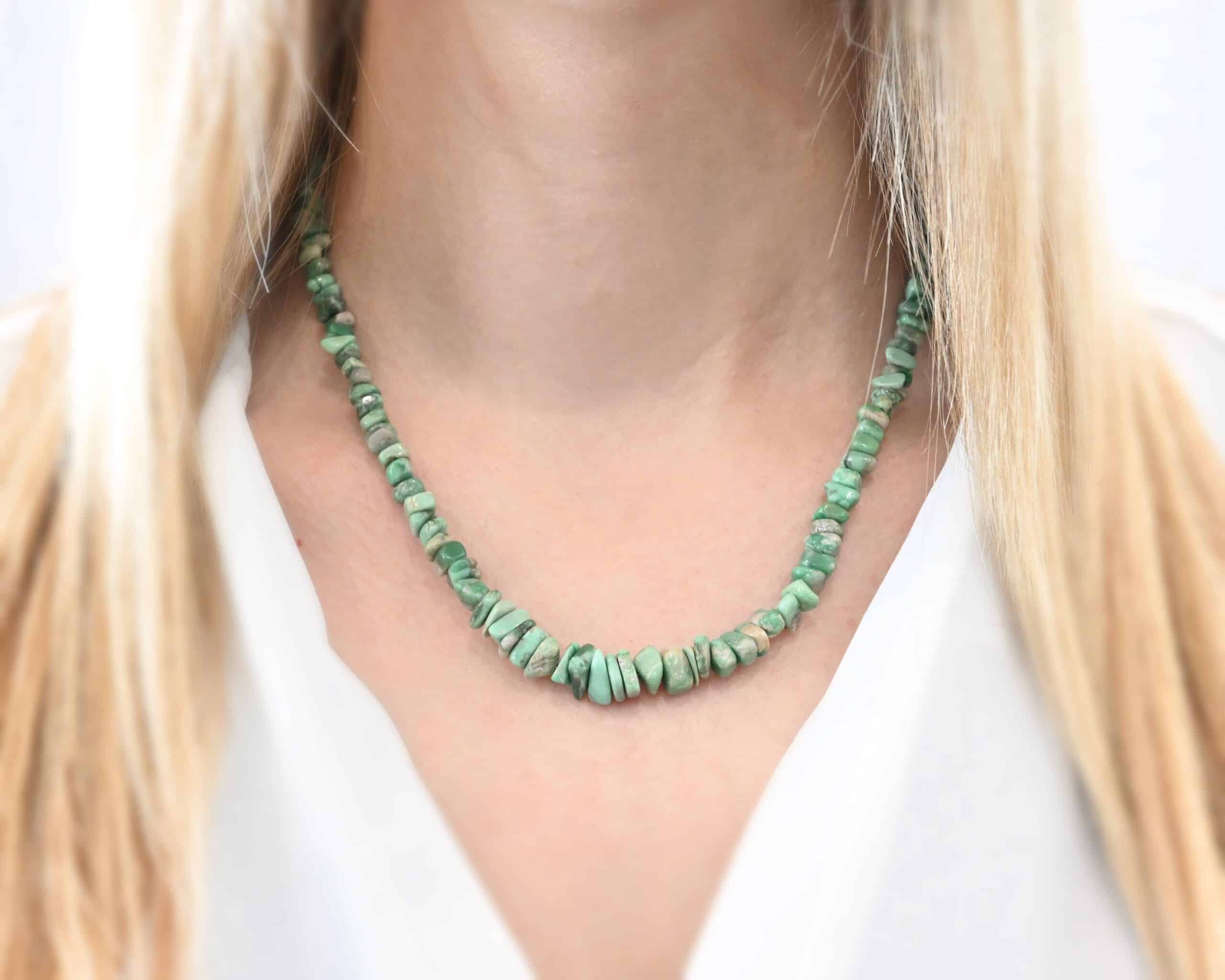 Photo of the "Rosalee" Necklace. Made out of sterling silver & variscite. The variscite are beaded tightly together onto wire. They are all varying shades of green, as well as different shapes. They graduate progressively as they get towards the center of the necklace. Necklace is worn by a model to demonstrate size.