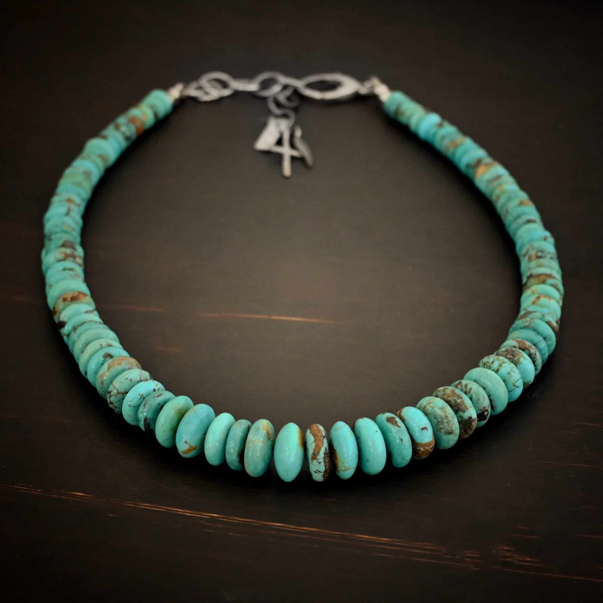 Bonnie Large Photo of the "Bonnie" Necklace. Made out of sterling silver and turquoise. Beads are varying shades of blueish green colors. The beads graduate in size as they get towards the center. Beads are strung tightly together. Necklace is lying against a dark background.