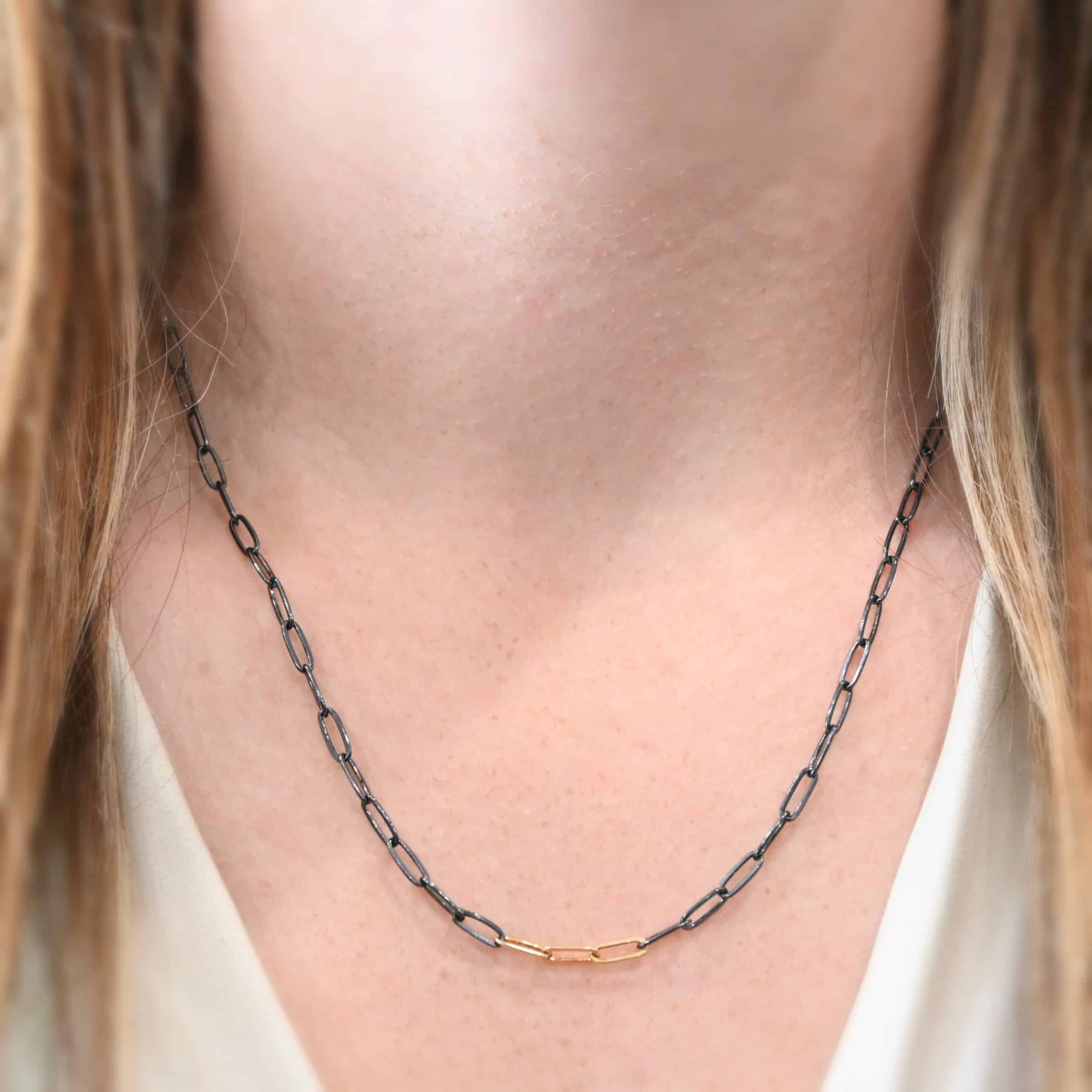 Lulu Link Chain "Lulu Link" Chain as shown on a model. Model is wearing a 20 inch oxidized sterling silver and gold filled Lulu Link Chain. Links are 8.5x3x2mm. Model is wearing a white v-neck shirt.