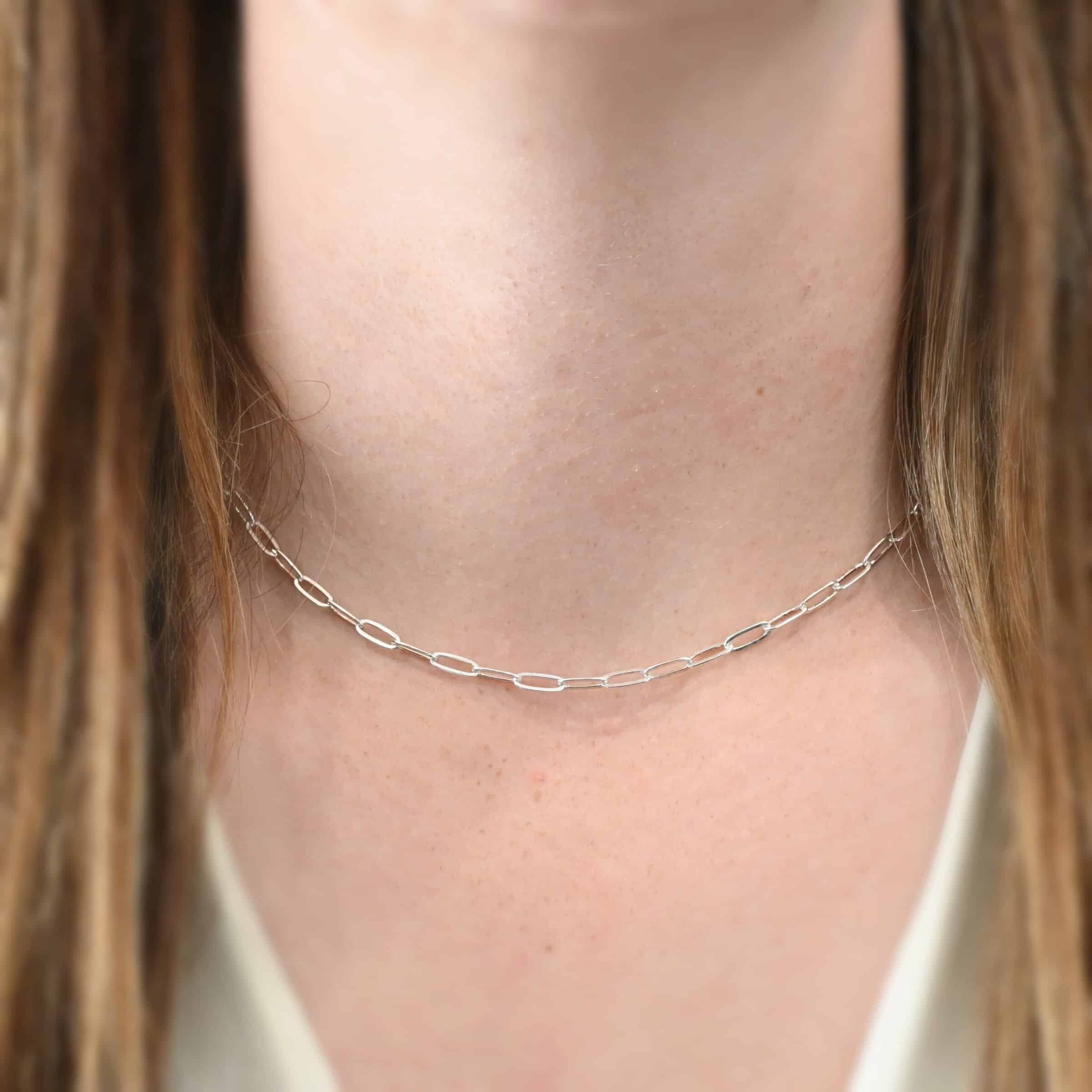 Lulu Link Chain "Lulu Link" Chain as shown on a model. Model is wearing a 16 inch shiny sterling silver Lulu Link Chain. Links are 8.5x3x2mm. Model is wearing a white v-neck shirt.