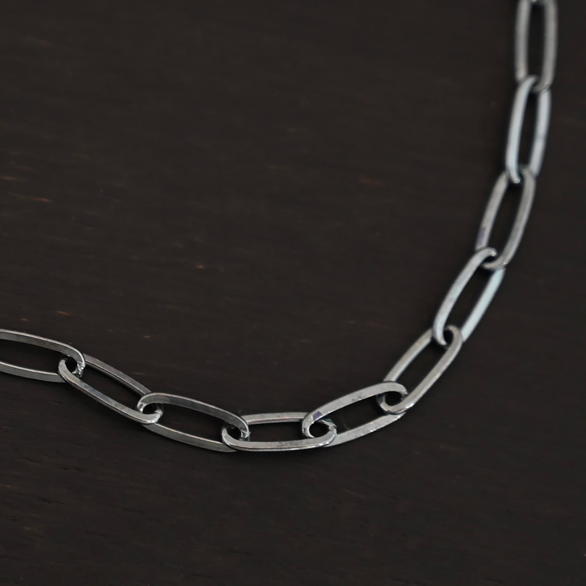 Lulu Link Oxidized "Lulu Link" Chain as shown up close. Shown is an oxidized Lulu Link Chain. Links are 8.5x3x2mm. Chain is lying against a dark background.