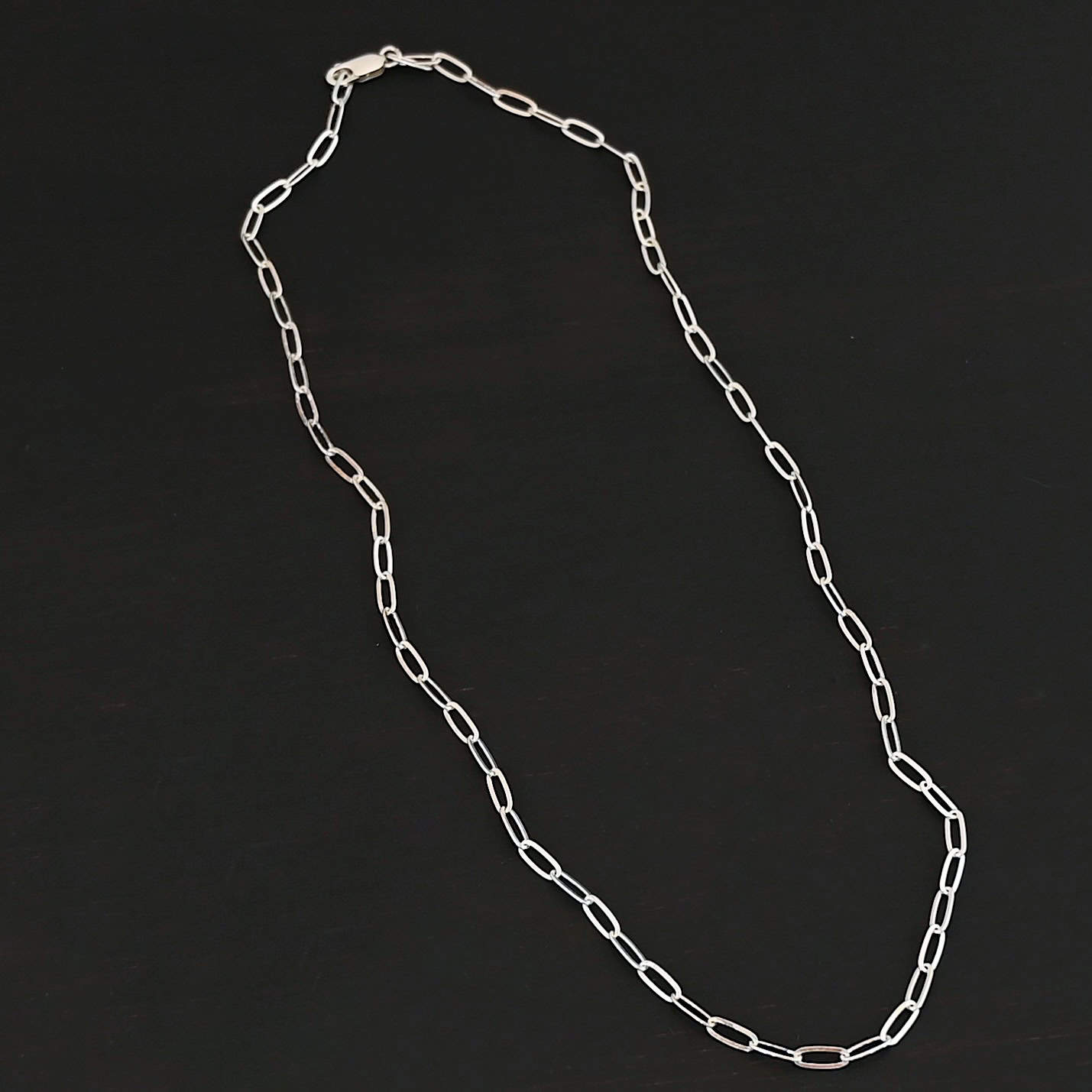Lulu Link Shiny "Lulu Link" Chain as shown up close. Shown is an shiny Lulu Link Chain. Links are 8.5x3x2mm. Chain is lying against a dark background.