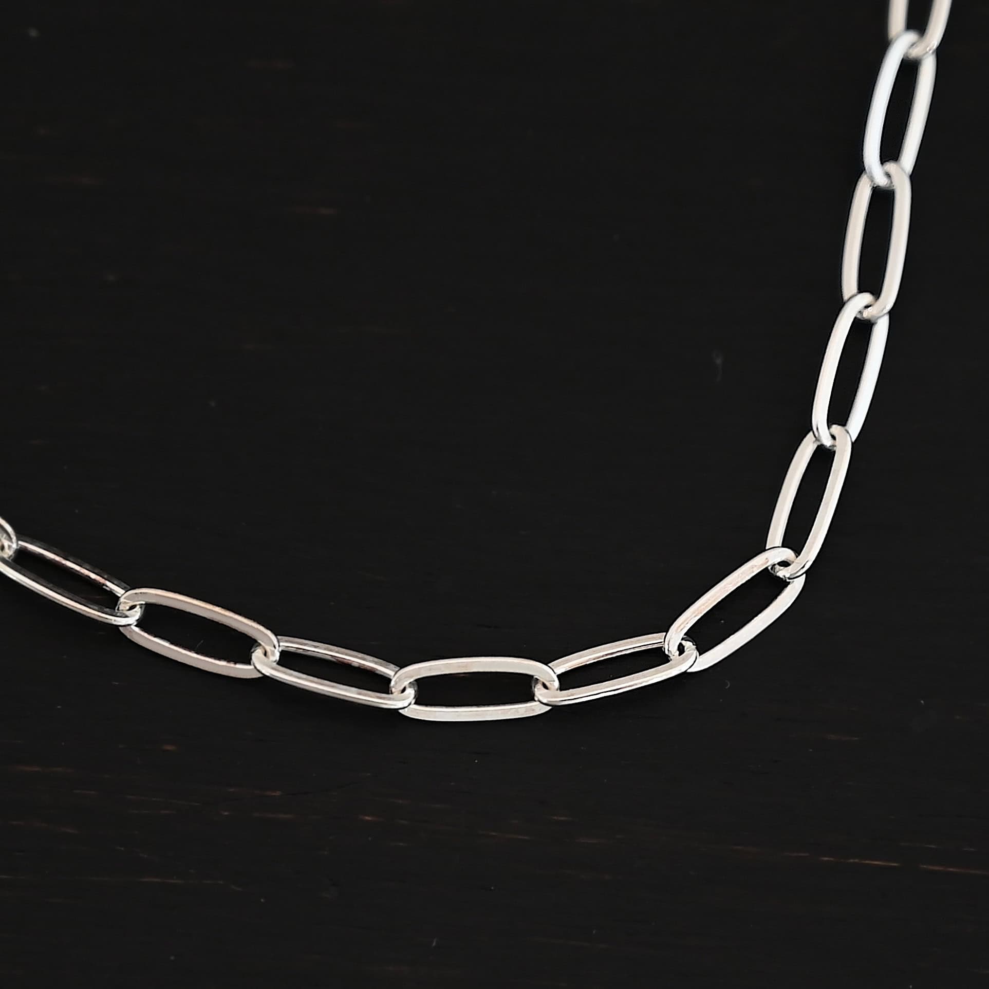 Lulu Link Shiny "Lulu Link" Chain as shown up close. Shown is an shiny Lulu Link Chain. Links are 8.5x3x2mm. Chain is lying against a dark background.