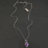 Close up of the "Bellflower" Necklace. Made out of sterling silver and amethyst. Amethyst is a slight oval, and is rose cut. Amethyst has three small silver dots on the top of it, and one small silver dot on the bottom, and is connected to the chain with three jump rings. Comes on a sterling silver "Cassandra" Chain. Necklace is set against a dark background.