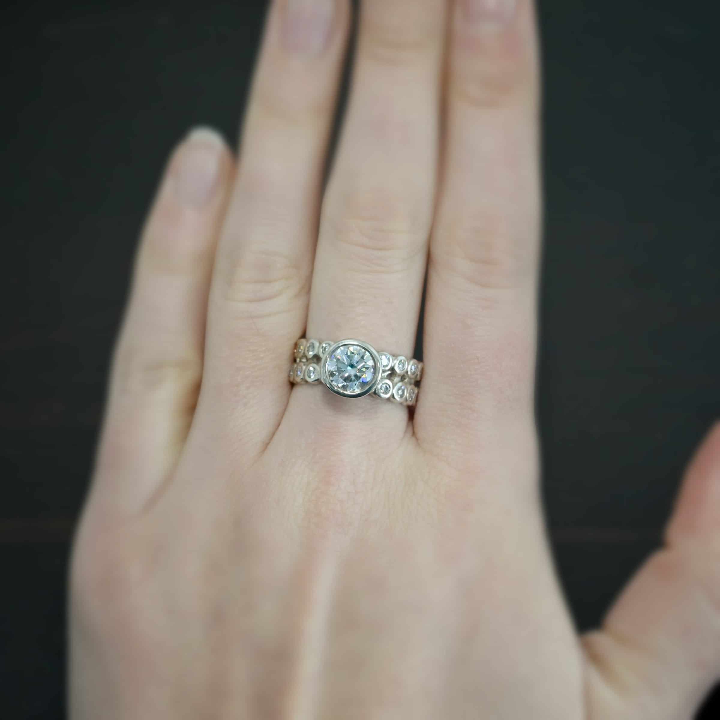 Heaven on Earth Ring Photo of the "Heaven On Earth" Ring. Made out of sterling silver and moissanites. There is a large moissanite in the center of the ring. The ring band is made of moissanites all the way around. There are two separate bands that are soldered together in the middle to create one band. Each band is made entirely out of moissanites that are set in silver and soldered together. Ring is worn by a model to demonstrate size.