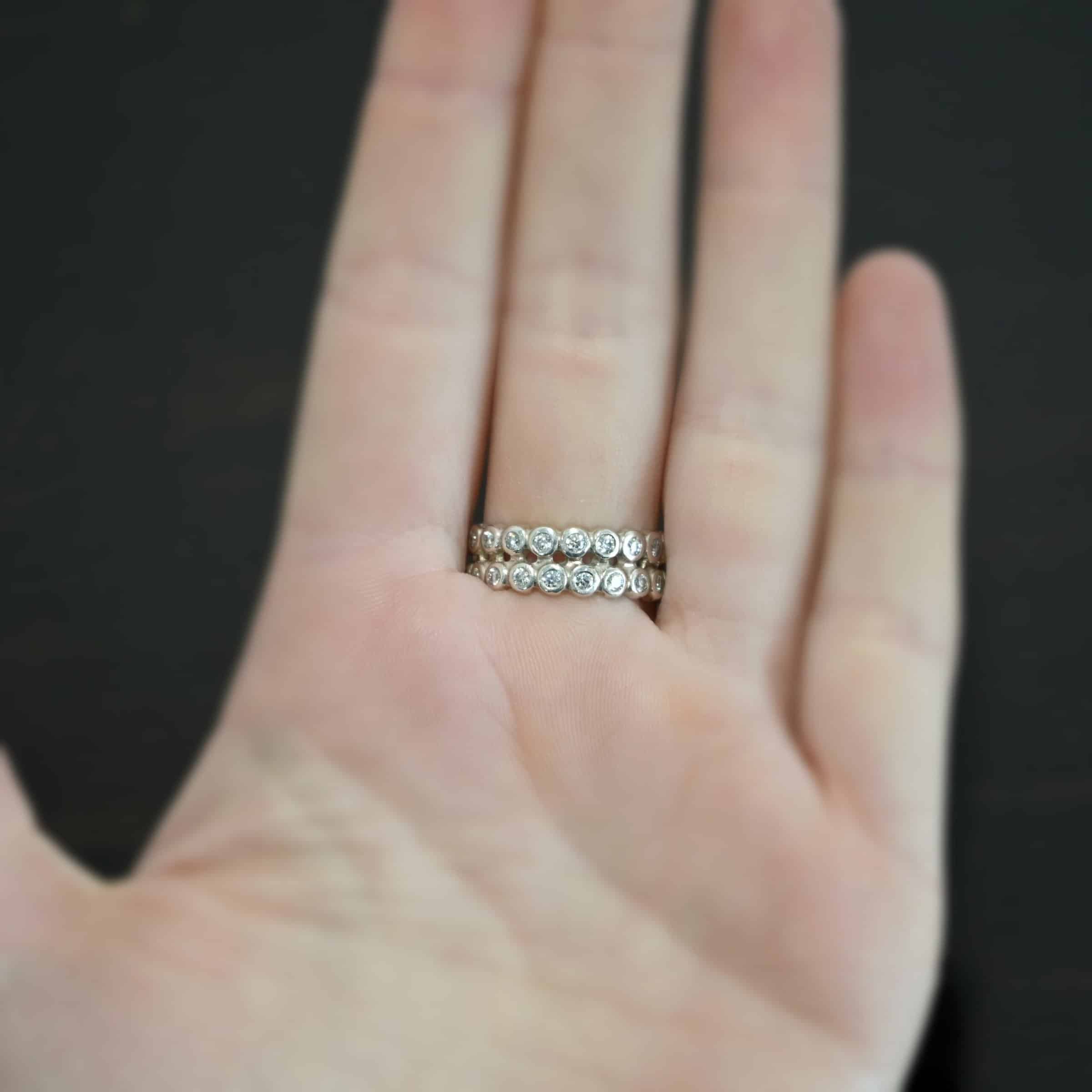 Heaven on Earth Ring Photo of the back of the "Heaven On Earth" Ring. Made out of sterling silver and moissanites. The ring band is made of moissanites all the way around. There are two separate bands that are soldered together in the middle to create one band. Each band is made entirely out of moissanites that are set in silver and soldered together. Ring is worn by a model to demonstrate size.