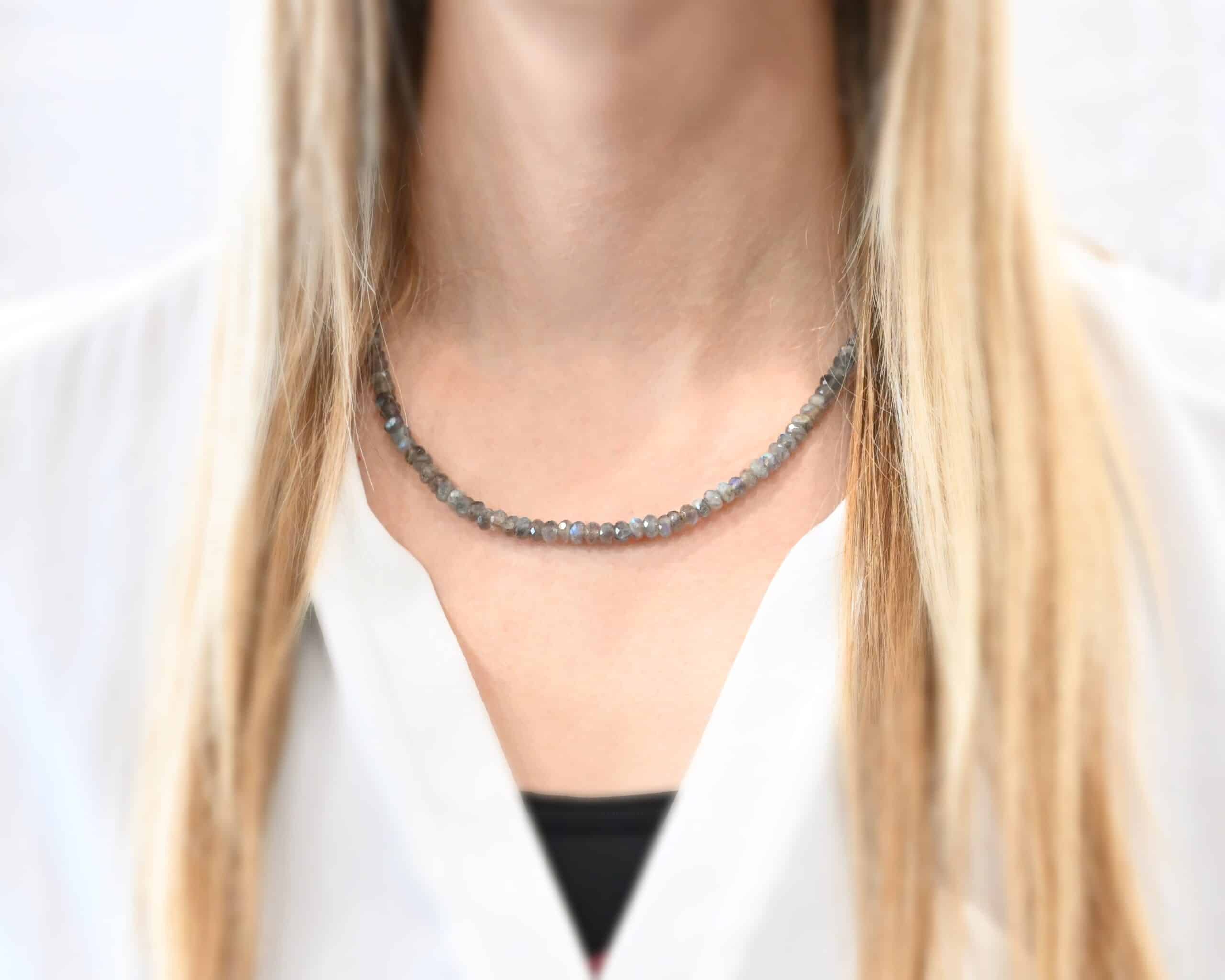 Lucy Labradorite Necklace Photo of the "Lucy Labradorite" Necklace. It is made of labradorite beads strung tightly together on silver wire. There are silver beads and crimps on the end of the necklace, and a silver clasp. Necklace is worn by a model to demonstrate size.