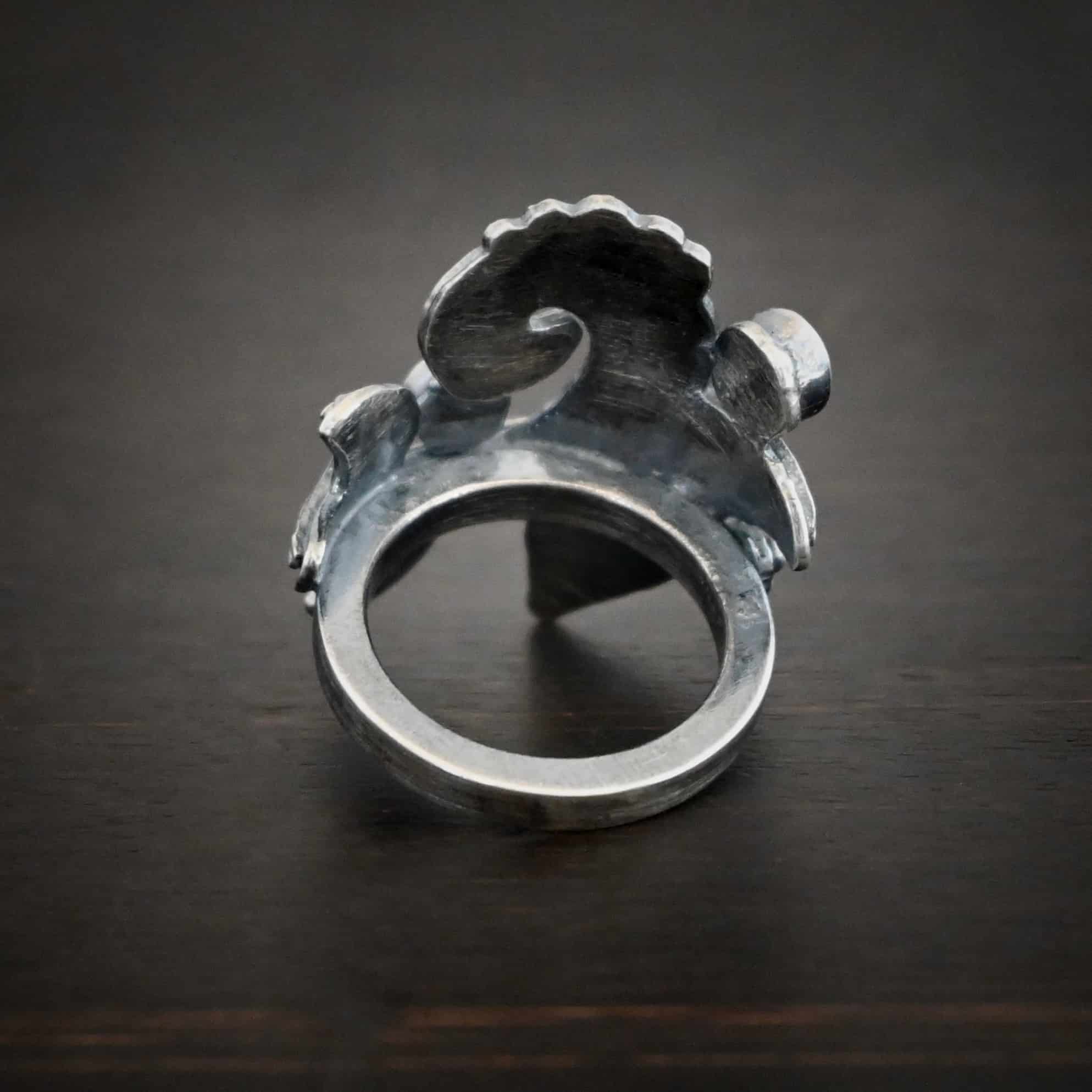 Purple Rain Ring Photo of the back of the purple rain ring. The back is a simple ring band. The back of the front of the ring is brushed oxidized sterling silver. Ring is sitting against a dark background.