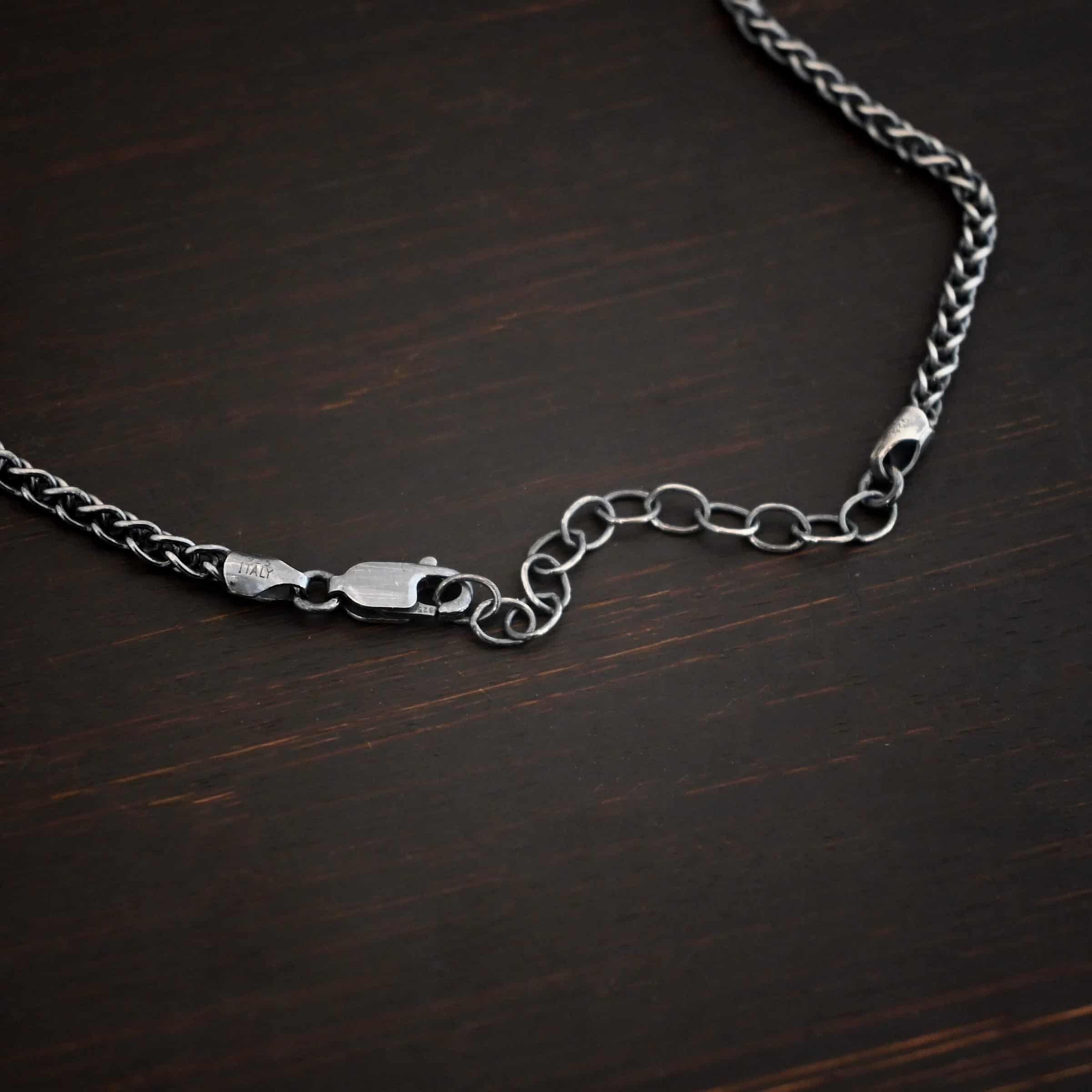 Frenchie Chain Close up of the "Frenchie" Chain. Sterling silver chain with an oxidized finish. It is a heavy french wheat chain that is 2.3mm. Chain is shown against a dark background. The lobster claw clasp and extension is shown close up.