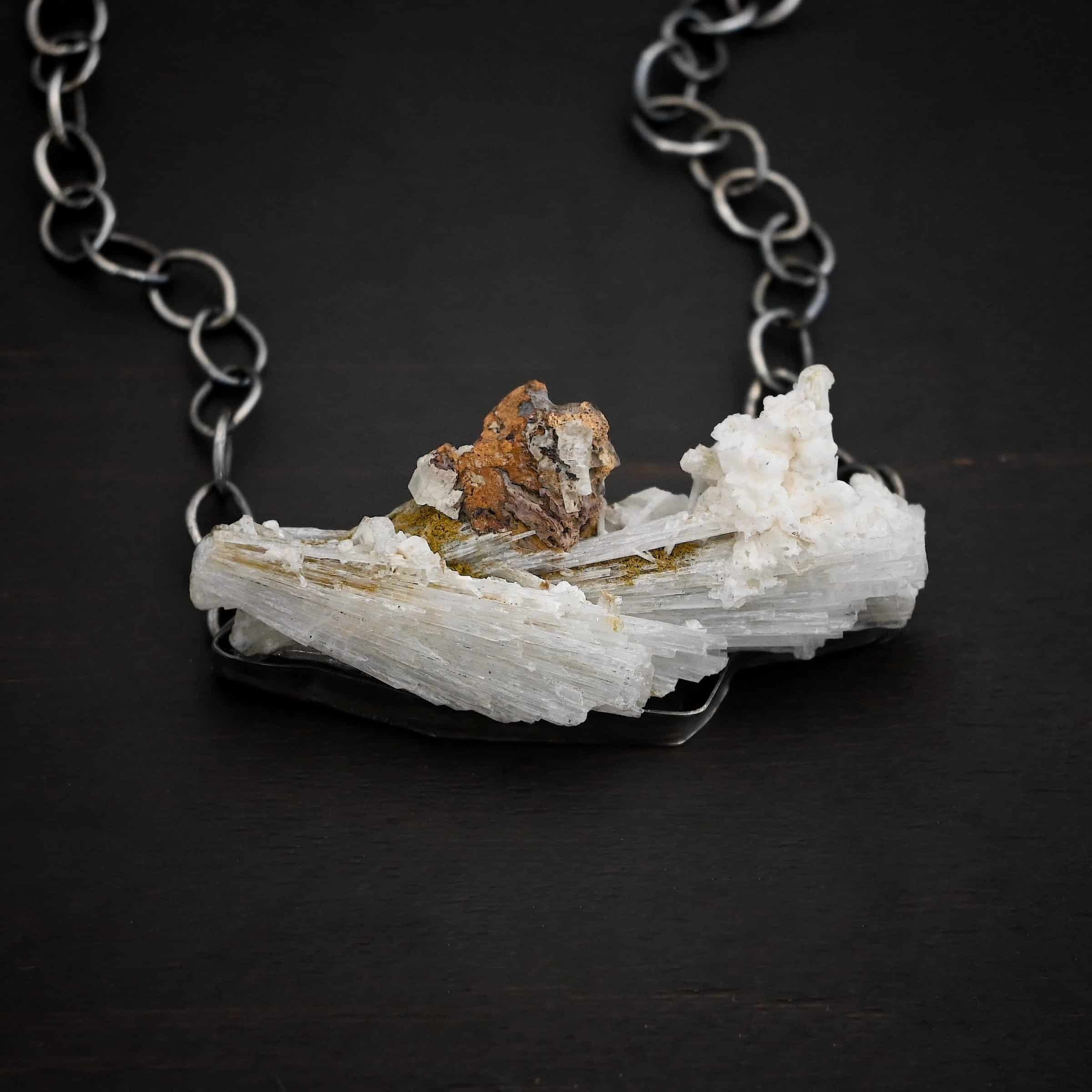 Driftwood Necklace Photo of the "Driftwood" Necklace. Necklace is made out of sterling silver and calcitite. Pendant measures 1x3." The calcitite is jagged, and rough cut. Comes on a sterling silver "Sky" chain that is oxidized with large circle links. Necklace is lying against a dark background.