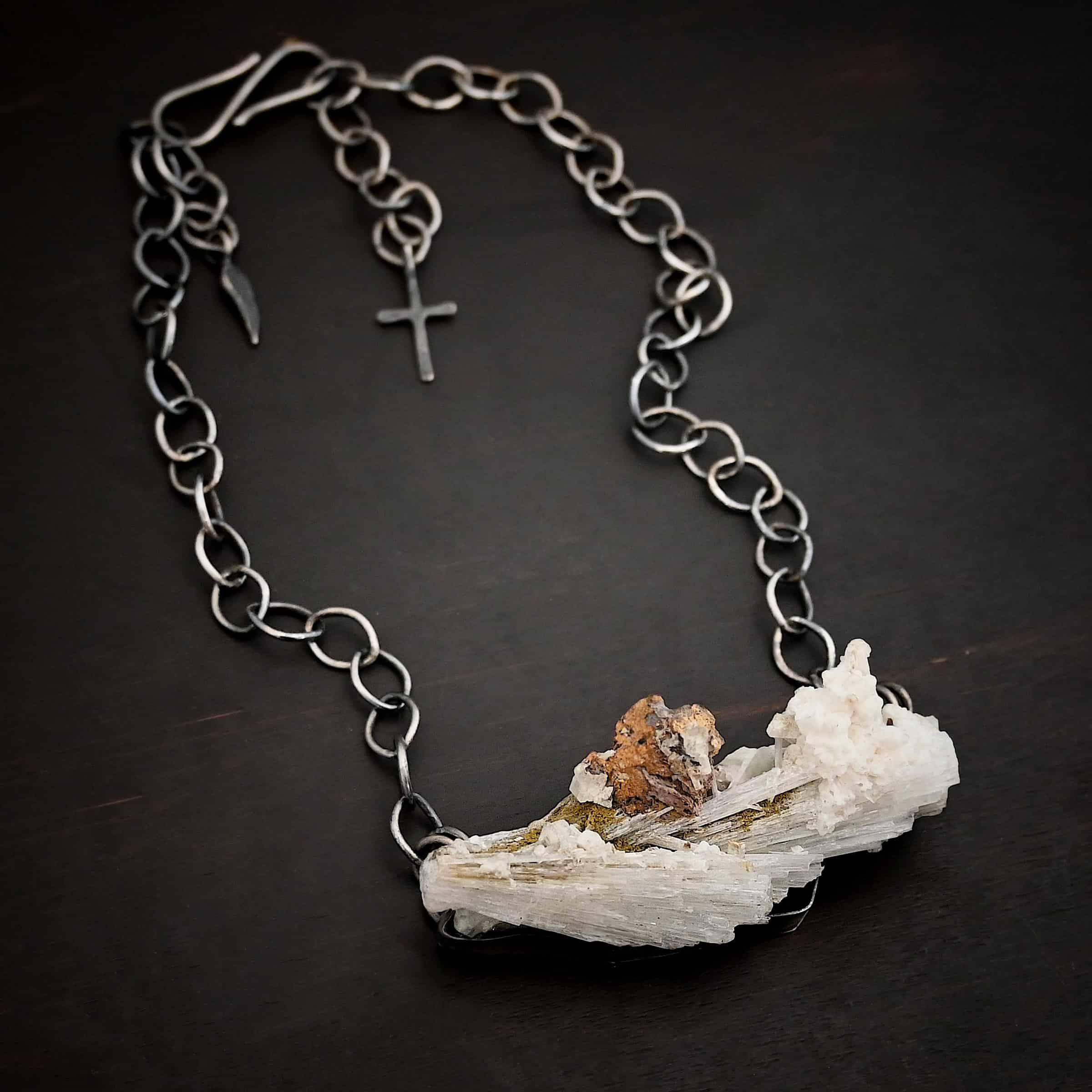 Driftwood Necklace Photo of the "Driftwood" Necklace. Necklace is made out of sterling silver and calcitite. Pendant measures 1x3." The calcitite is jagged, and rough cut. Comes on a sterling silver "Sky" chain that is oxidized with large circle links. Necklace is lying against a dark background.
