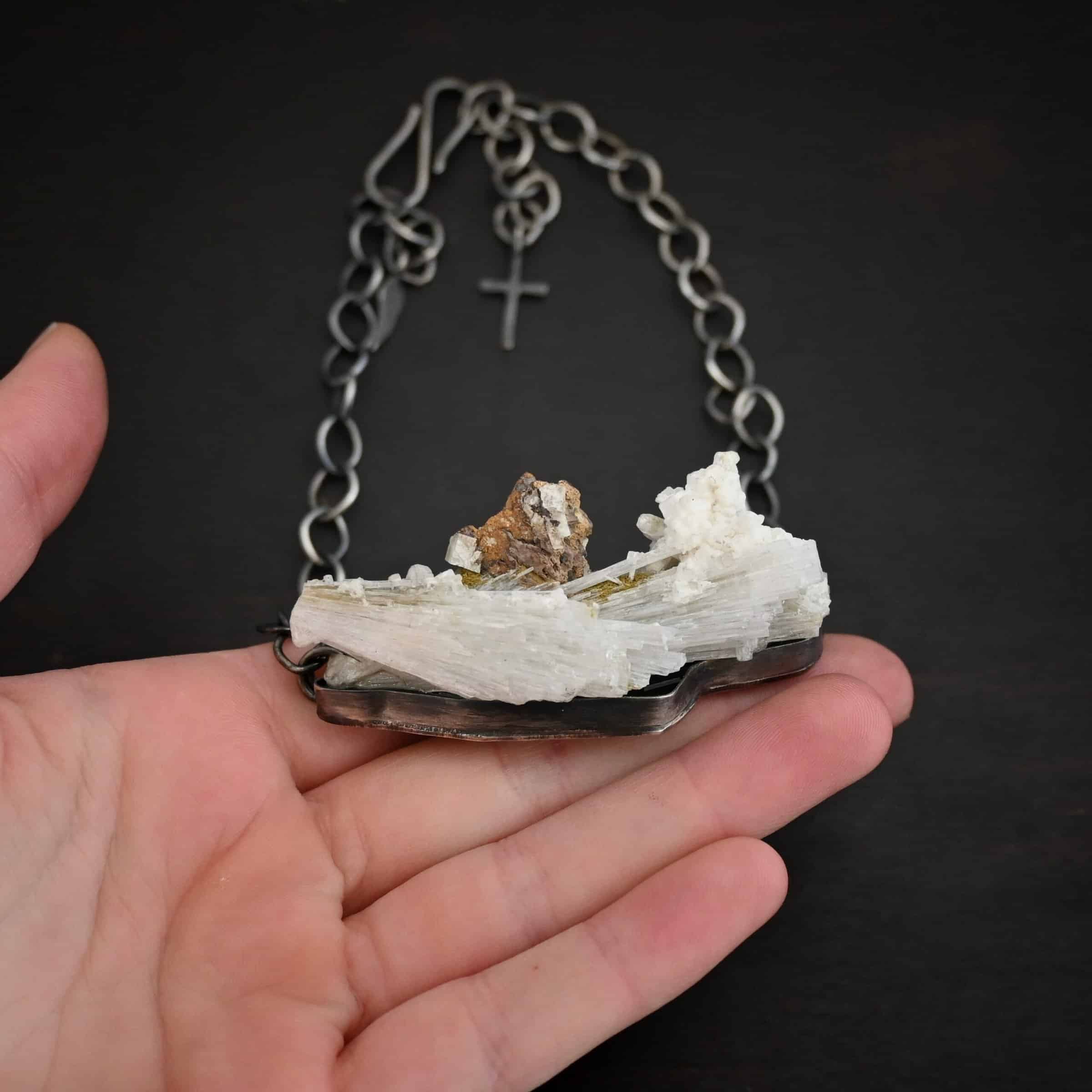Driftwood Necklace Photo of the "Driftwood" Necklace. Necklace is made out of sterling silver and calcitite. Pendant measures 1x3." The calcitite is jagged, and rough cut. Comes on a sterling silver "Sky" chain that is oxidized with large circle links. Necklace is lying against the fingertips of a hand to demonstrate size.