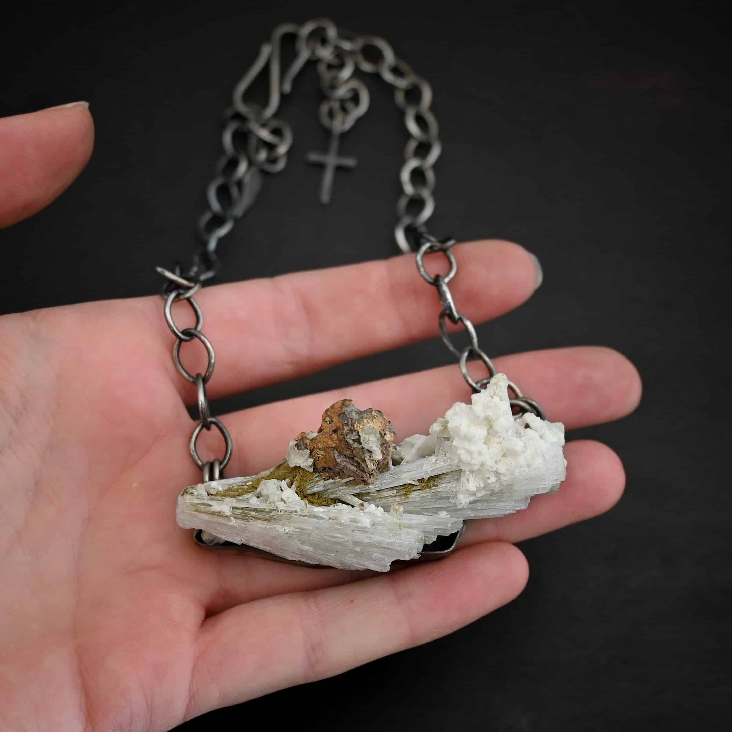 Driftwood Necklace Photo of the "Driftwood" Necklace. Necklace is made out of sterling silver and calcitite. Pendant measures 1x3." The calcitite is jagged, and rough cut. Comes on a sterling silver "Sky" chain that is oxidized with large circle links. Necklace is lying against the fingertips of a hand to demonstrate size.