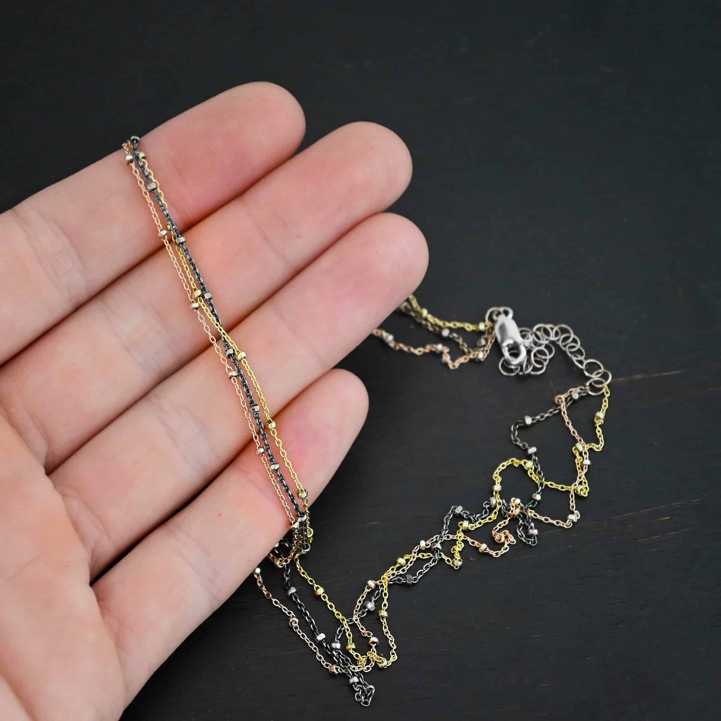 Champagne in Paris ox "Champagne In Paris" Chain as shown up close. oxidized Sterling Silver, 14K Rose Gold Filled, & 14K Yellow Gold Filled chain 1.2mm thick. Chain is lying against the fingertips of a hand to demonstrate size.