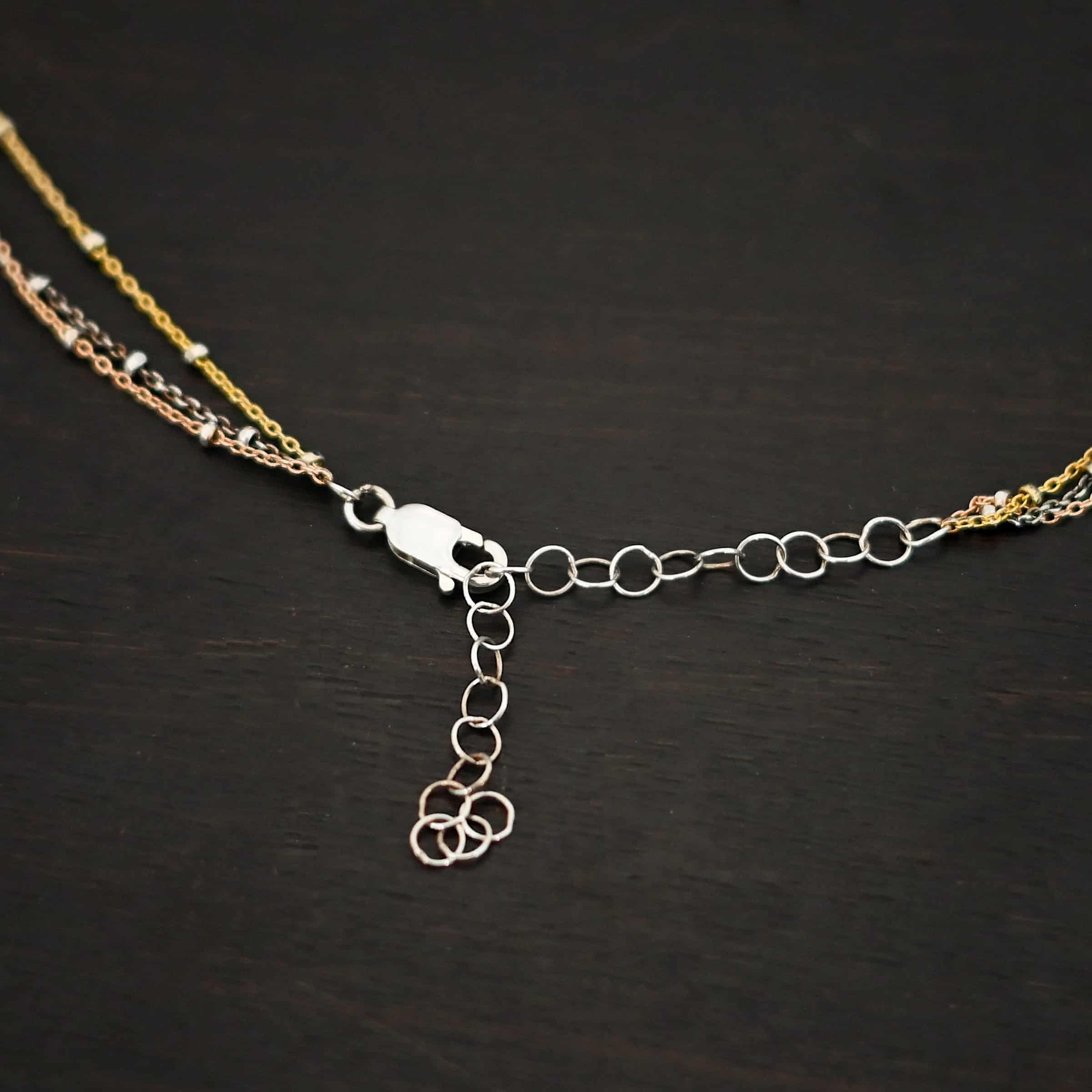 Champagne in Paris ox "Champagne In Paris" Chain as shown up close. shiny Sterling Silver, 14K Rose Gold Filled, & 14K Yellow Gold Filled chain 1.2mm thick. Chain is shown against a dark background. Chain has a shiny lobster claw clasp with a two inch sterling silver chain extension.