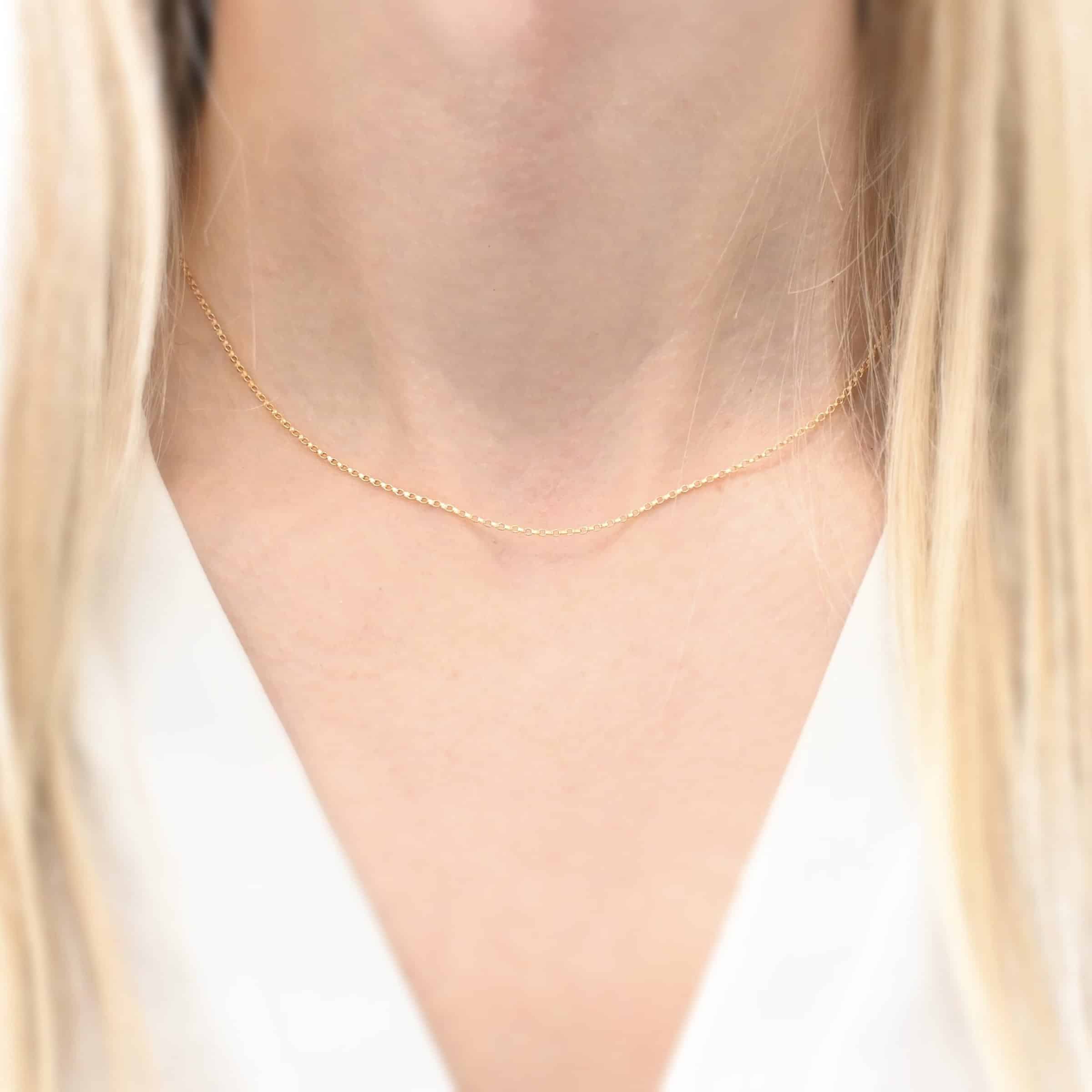Close up of the "Jessica Rolo" Chain as shown on a model. Chain is 1.2mm thick and 14K Gold Filled over sterling silver. Chain is 16" long as shown on model and model is wearing a white v-neck shirt.