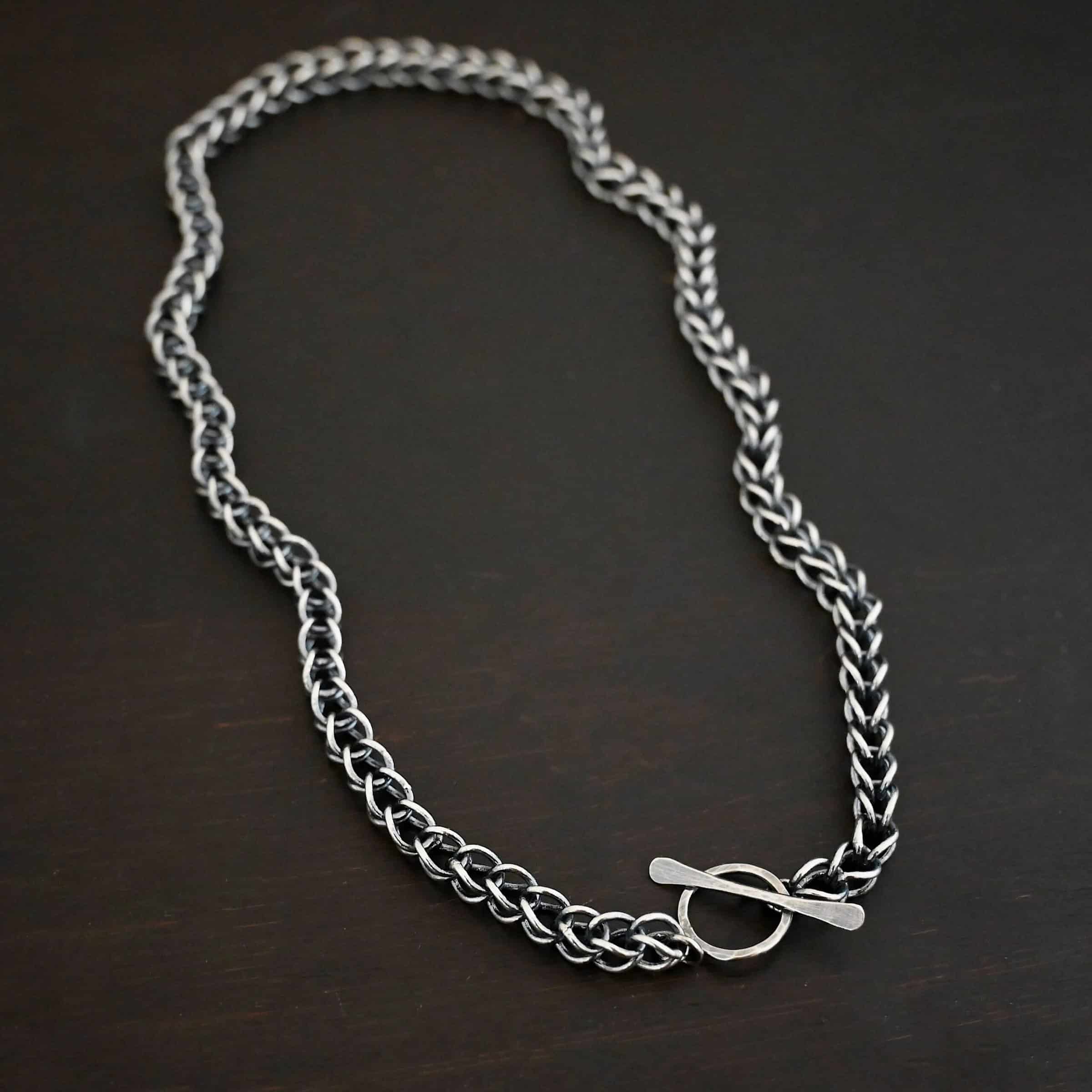 Gretchen Chain Photo of the "Gretchen" Chain. Chain is made out of sterling silver and oxidized. Chain is a viking knit chain, and approximately 18" long. Chain has a s hook clasp. Chain is lying against the fingertips of a hand to demonstrate size.