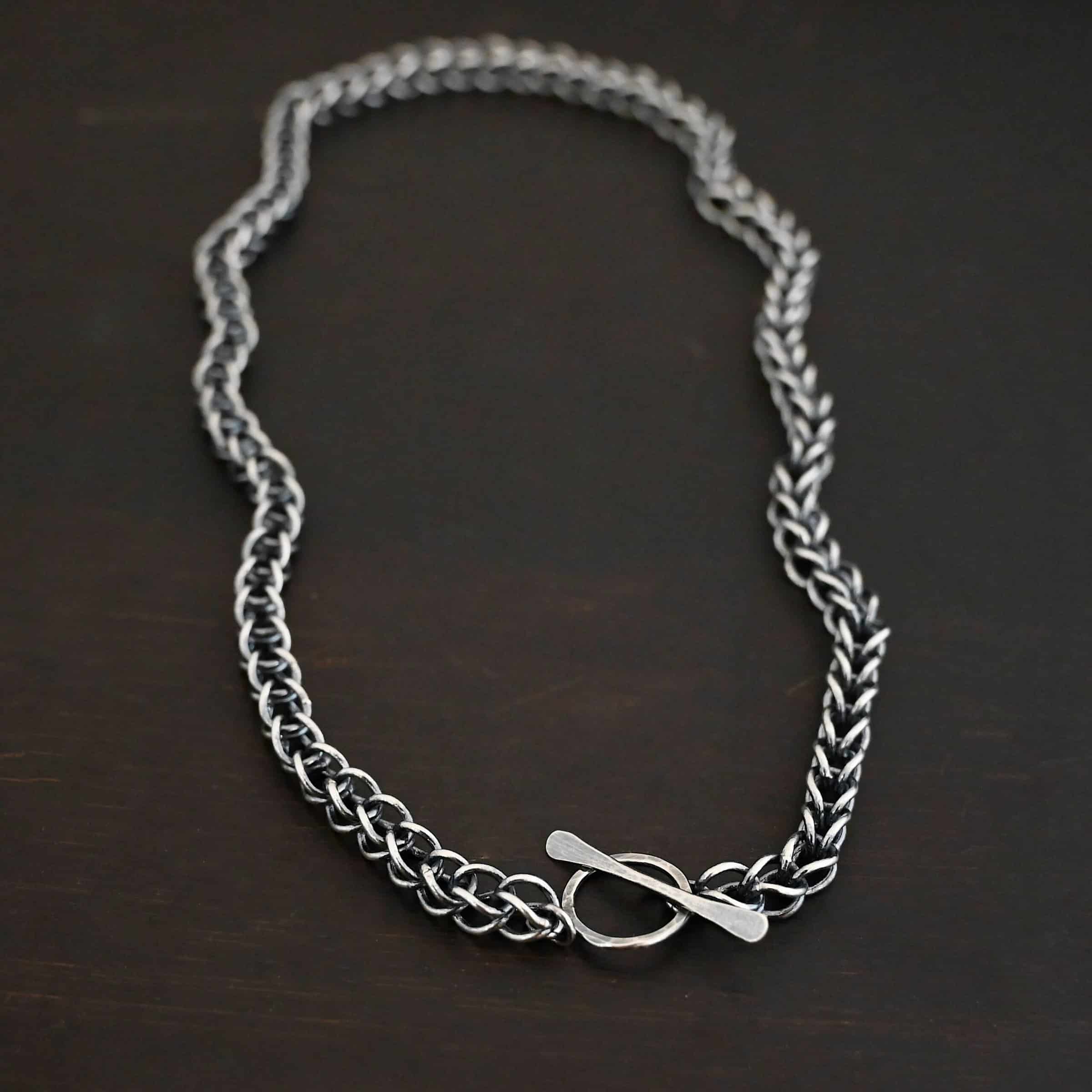 Gretchen Chain Photo of the "Gretchen" Chain. Chain is made out of sterling silver and oxidized. Chain is a viking knit chain, and approximately 18" long. Chain has a s hook clasp. Chain is lying against the fingertips of a hand to demonstrate size.