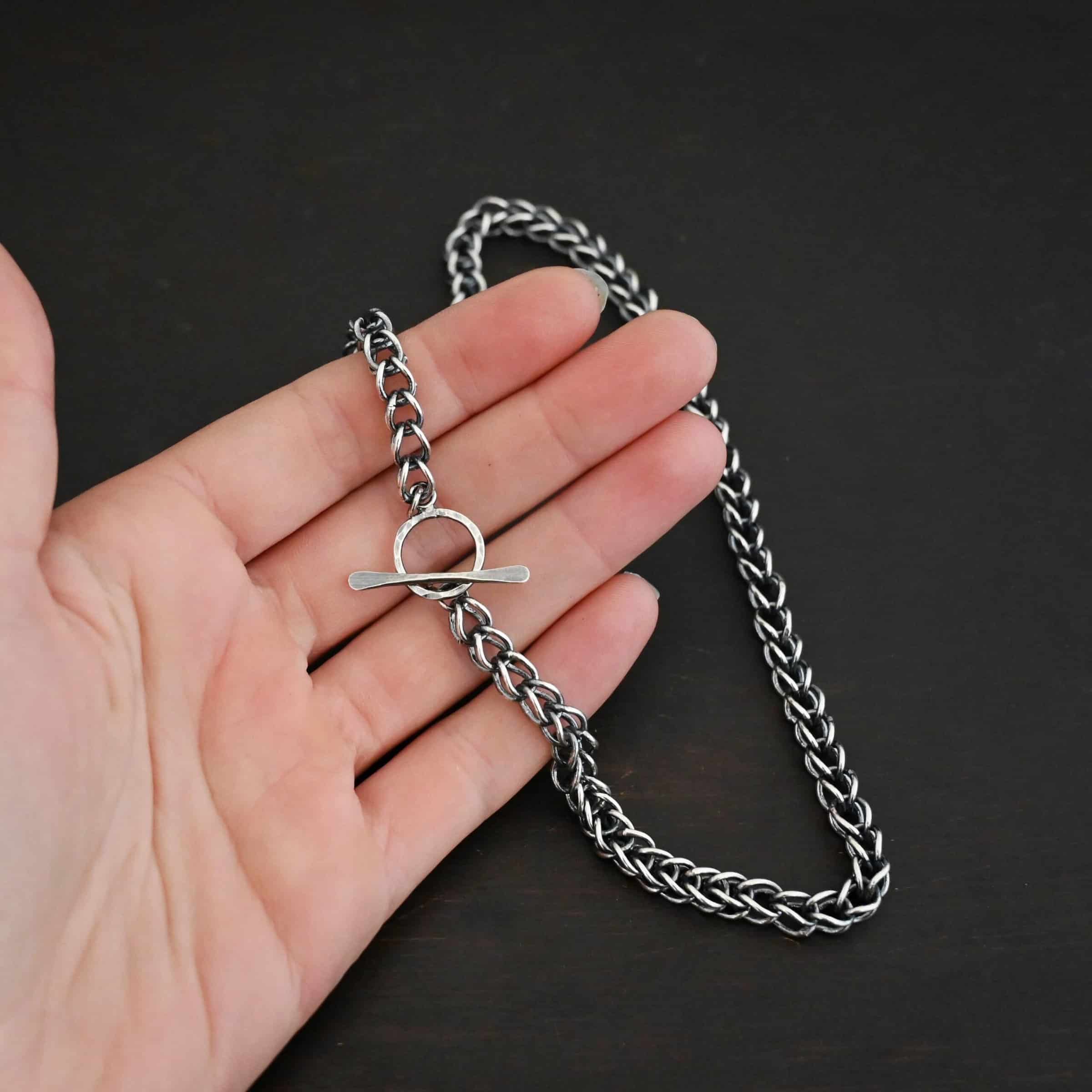 Gretchen Chain Photo of the "Gretchen" Chain. Chain is made out of sterling silver and oxidized. Chain is a viking knit chain, and approximately 18" long. Chain has a toggle hook clasp. Chain is lying against the fingertips of a hand to demonstrate size.