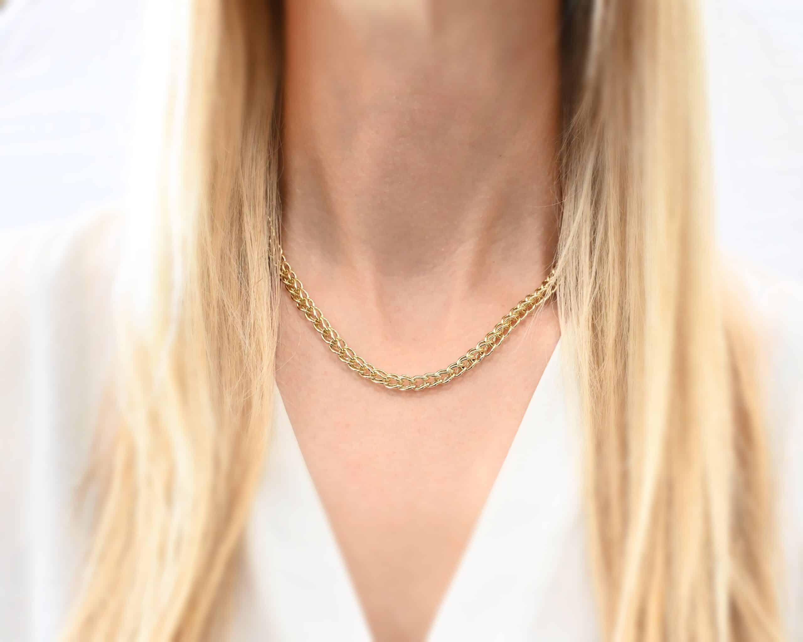 Gretchen Chain Photo of the "Gretchen" Chain. Chain is made out of 18k gold. Chain is a viking knit chain, and approximately 18" long. Chain has a toggle clasp. Necklace is worn by a model. Model is wearing a white v-neck shirt.