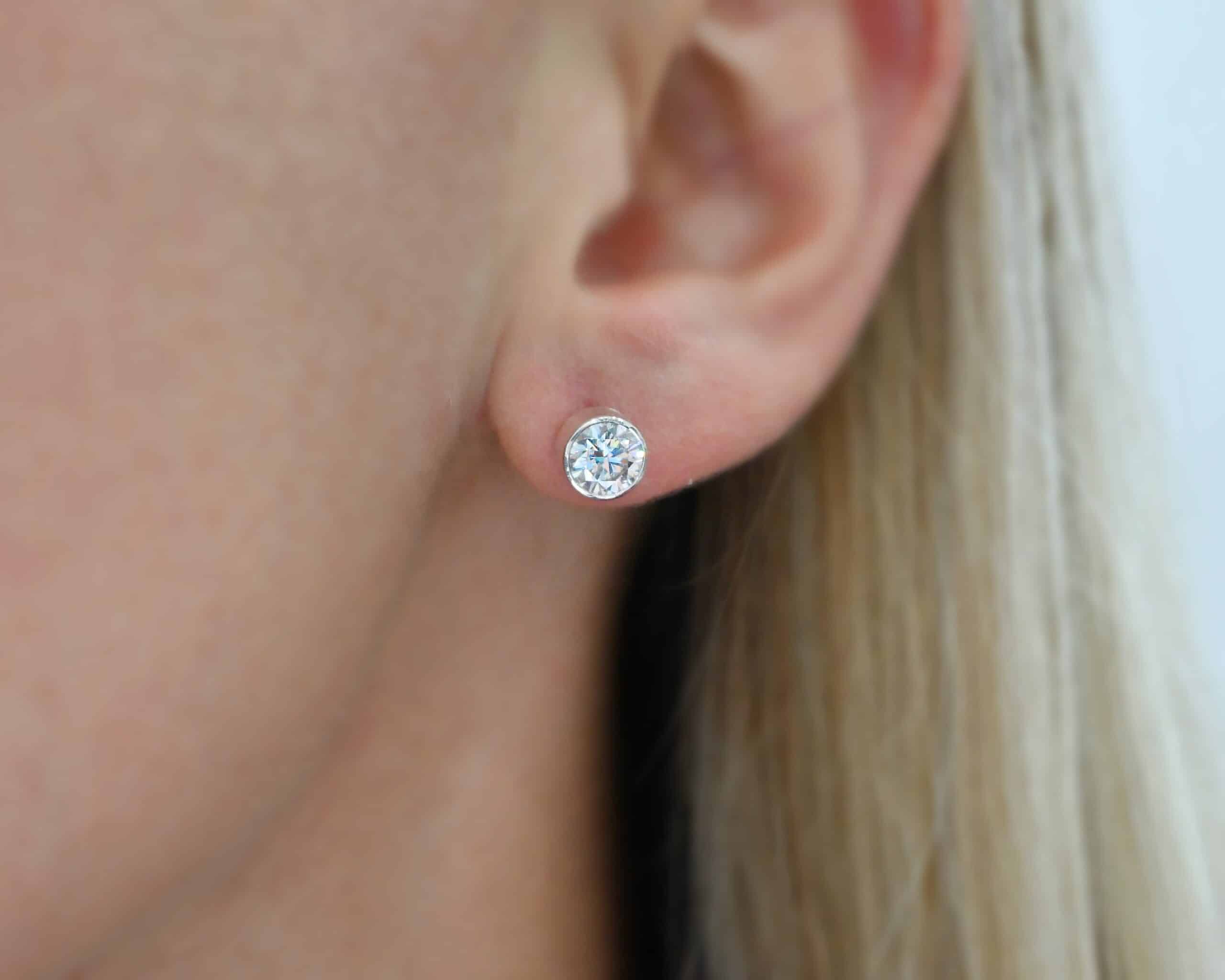 Photo of the "Betina" Earrings. Made out of sterling silver and moissanites. Each earring has a moissanite in the center that is set in sterling silver. Earrings are worn by a model to demonstrate size.