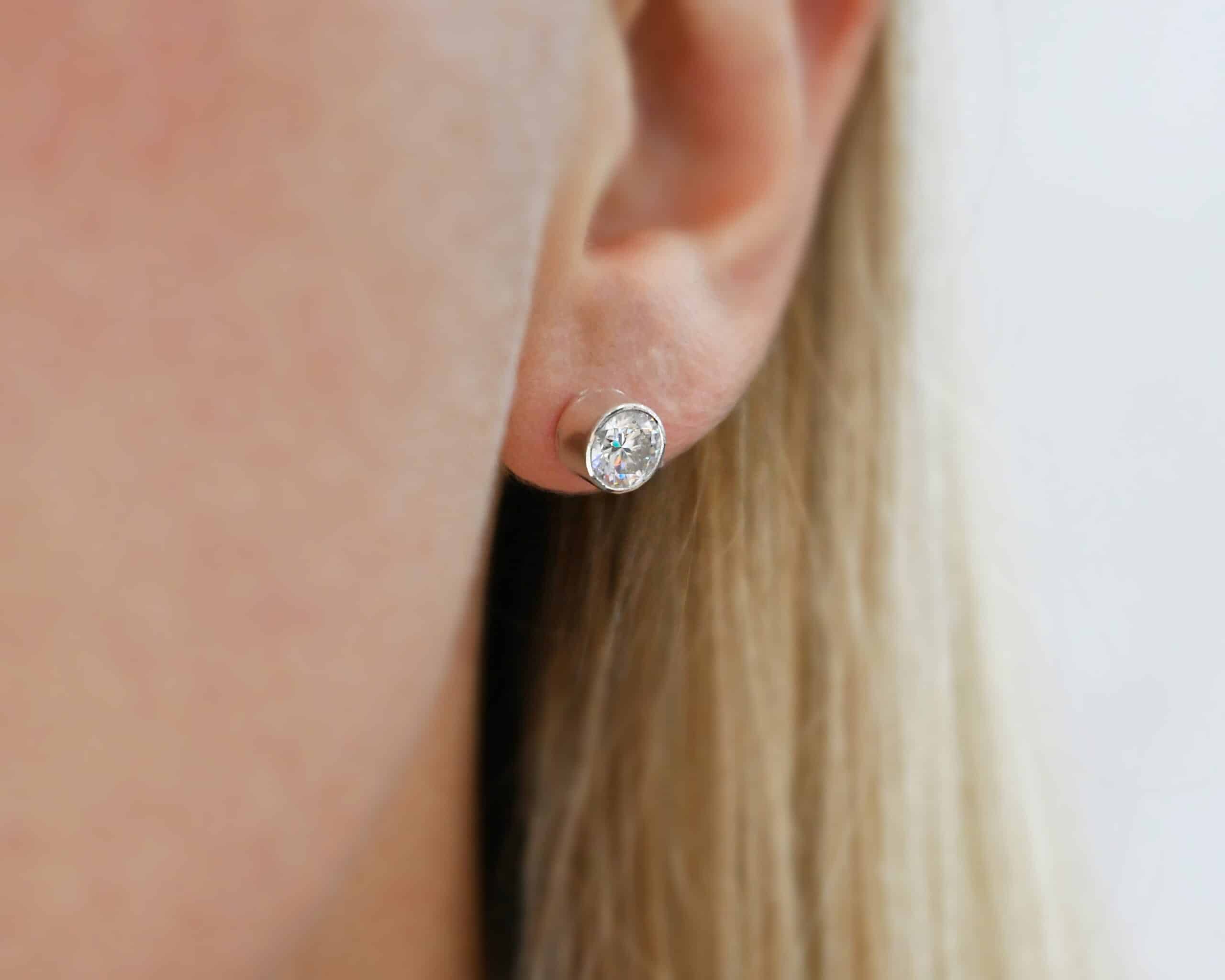 Photo of the "Betina" Earrings. Made out of sterling silver and moissanites. Each earring has a moissanite in the center that is set in sterling silver. Earrings are worn by a model to demonstrate size.