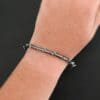The "Ice Berry" Bangle as shown on a model. Bangle is made out of sterling silver, and has a sterling silver line wrapping around it, as well as silver dots scattered around the bangle. Model is wearing the bangle on wrist to demonstrate the size.