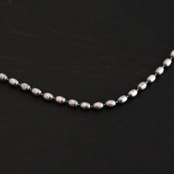 "Bryn Beaded" Chain as shown up close. Chain is shown as oxidized with 1.5mm oval beads that have very little space between them. Chain is shown against a dark background.