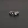 Heart Of Silver Ring New Photo of the "Heart Of Silver" Ring. There is a large moissanite in the center of the ring, with two smaller moissanites on each side of it, making for five total moissanites on the ring. Ring is set against a dark background.