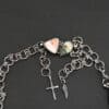 The "Look For Adventure" Necklace clasp. Made out of sterling silver and ocean jasper. There are two ocean jasper that make up the clasp. One is teardrop shaped and the other is triangle shaped. The teardrop shaped ocean jasper is on the left side of the clasp. It is dark green from the tip of the teardrop to the middle of the stone. The bottom half of the stone is yellow with white spots. The triangle shaped ocean jasper is on the right side of the clasp. It is orange from the top point of the triangle to the center. The bottom half of the triangle is white. The clasp is attached to a handmade sterling silver chain that has large circular loops that are hammered and oxidized. The circle loops are attached together with jump rings. Clasp is sitting against a dark background.
