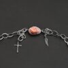 Clasp for the "Inner Planet" Necklace. There is a small, oval, red, white, and orange agate with two hooks on the back for the links to connect to, as well as a small cross and angel wing charm.