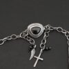 The "Mysteries Beyond" Necklace clasp. Handmade out of sterling silver and five black onyx. There is a black onyx for the clasp of the necklace. Clasp has two links on the back that each end of the chain connects to. There is a small cross and angel wing charm on the clasp. Necklace is set against a dark background.