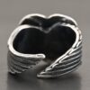 Close up of the back of the "Untamable Spirit" Ring. A curved angel wing creates each side of the band and they meet closely at the back, but do not touch. Ring is set against a dark background.
