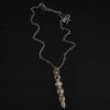 Photo of the "Daybreak" Necklace. Made out of sterling silver, gold, and diamond. There are nine diamonds, all in a straight line, that create the pendant of the necklace. Five of the diamonds are different shapes, sizes, and colors. Each of these diamonds are separated by small, circular diamonds, which there are four of. The top of the pendant starts with a large diamond, then a small one, and keeps alternating until the final diamond is a large one. There is a large loop soldered to the back of the top of the pendant with four gold jump rings attached to it. Going through the jump rings is the silver chain of the necklace. The chain of the necklace has gold loops scattered around it. Necklace is lying against a dark background.
